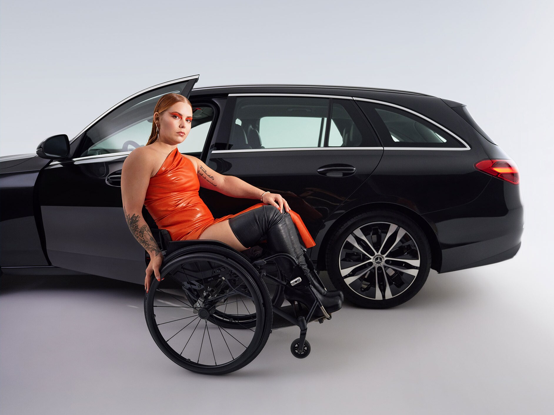 Pohľad zboku na kombi Triedy C upravené na vozidlo vhodné pre invalidov a žena na invalidnom vozíku.