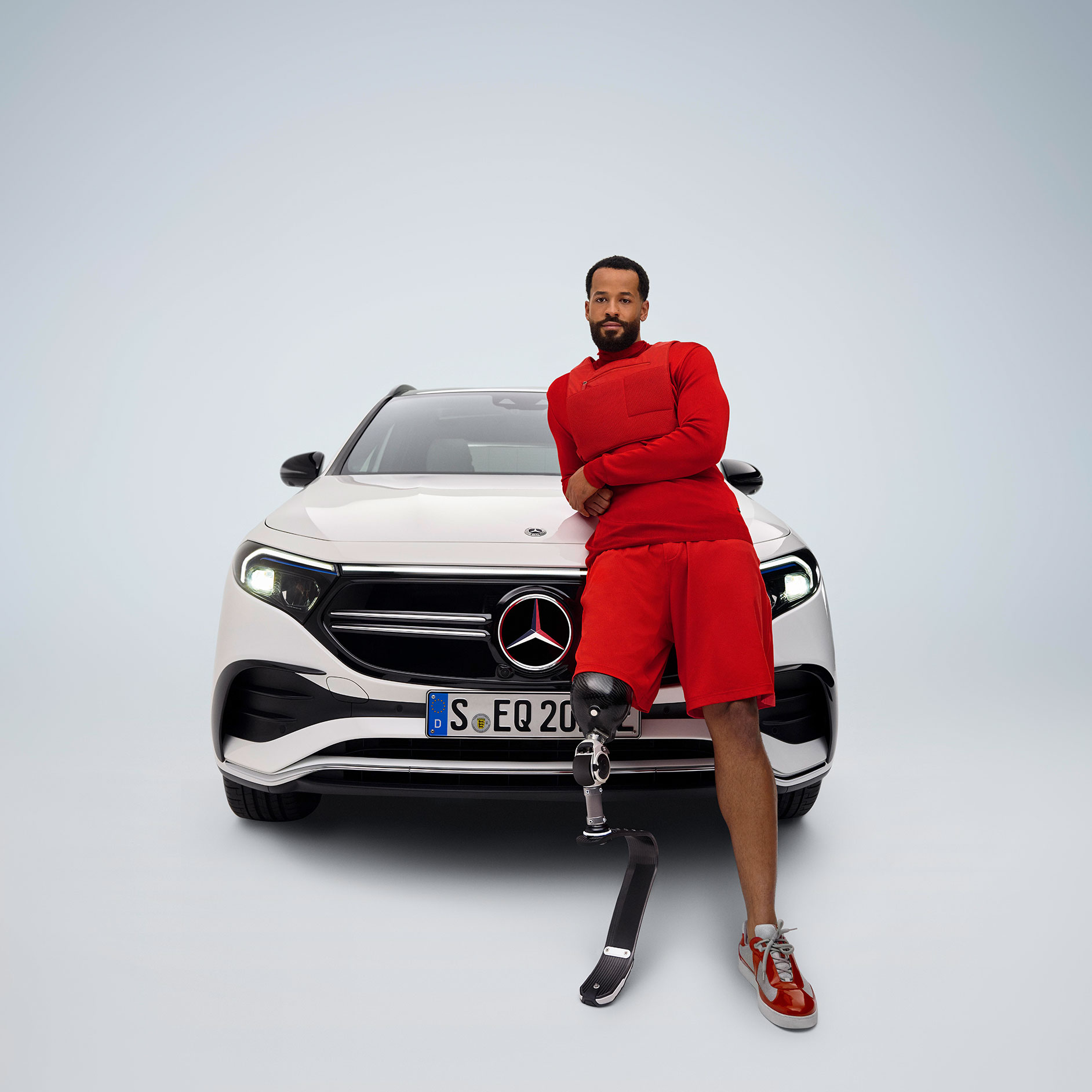 Prispôsobenie pedálov | Pomôcky na ovládanie vozidla | Mercedes-Benz Pohľad spredu na vozidlo Mercedes-Benz EQA upravené na vozidlo vhodné pre invalidov a muž s protézou nohy.