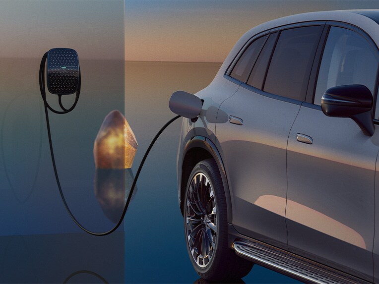 Pohľad zboku na EQS SUV počas nabíjania, ktorá je pripojená k nabíjacej skrinke Mercedes-Benz.