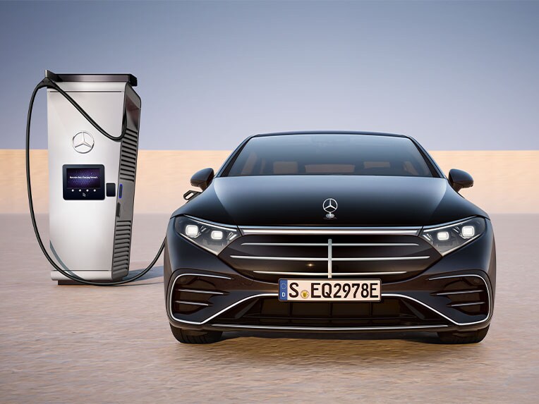 Pohľad spredu na EQS sedan od značky Mercedes-Benz počas nabíjania na verejnej nabíjacej stanici.