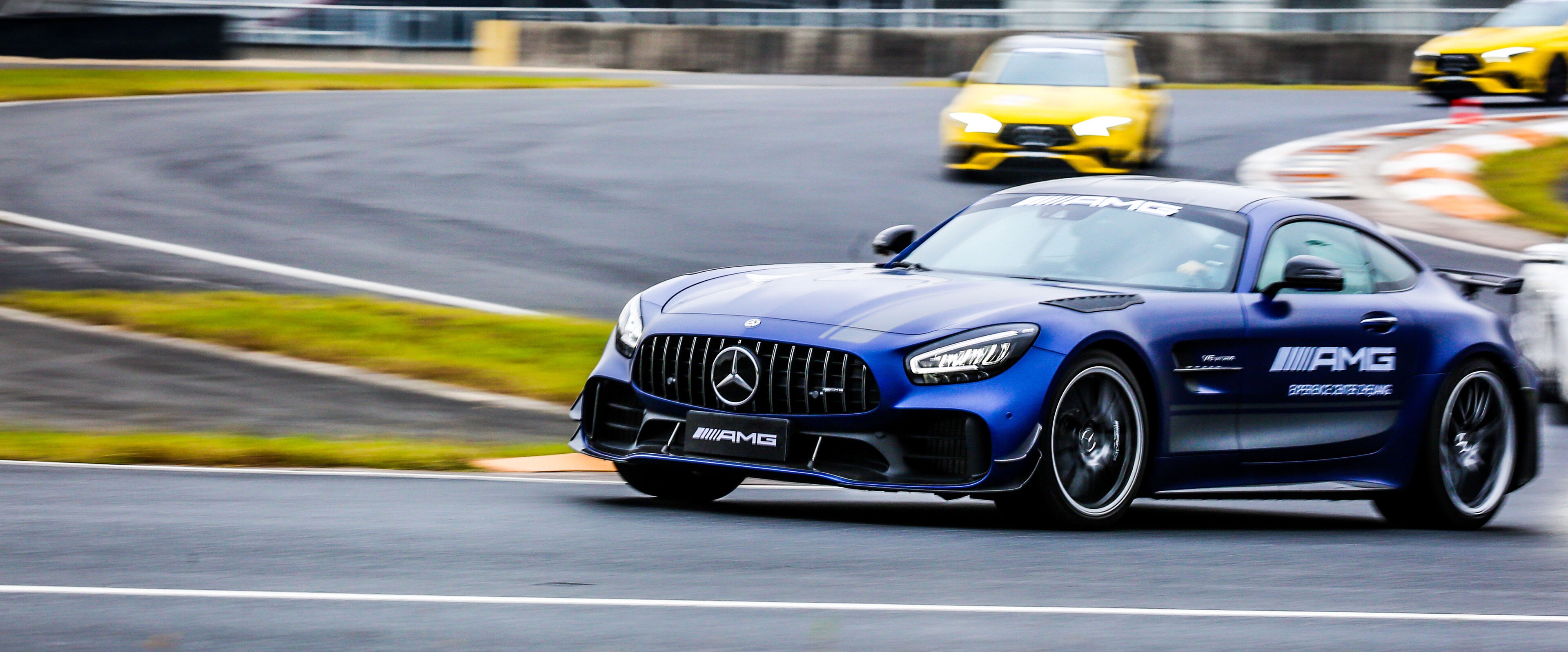 Tmavomodrý Mercedes-AMG GT R jazdí po pretekárskej trati a prenasledujú ho ďalšie dve autá.