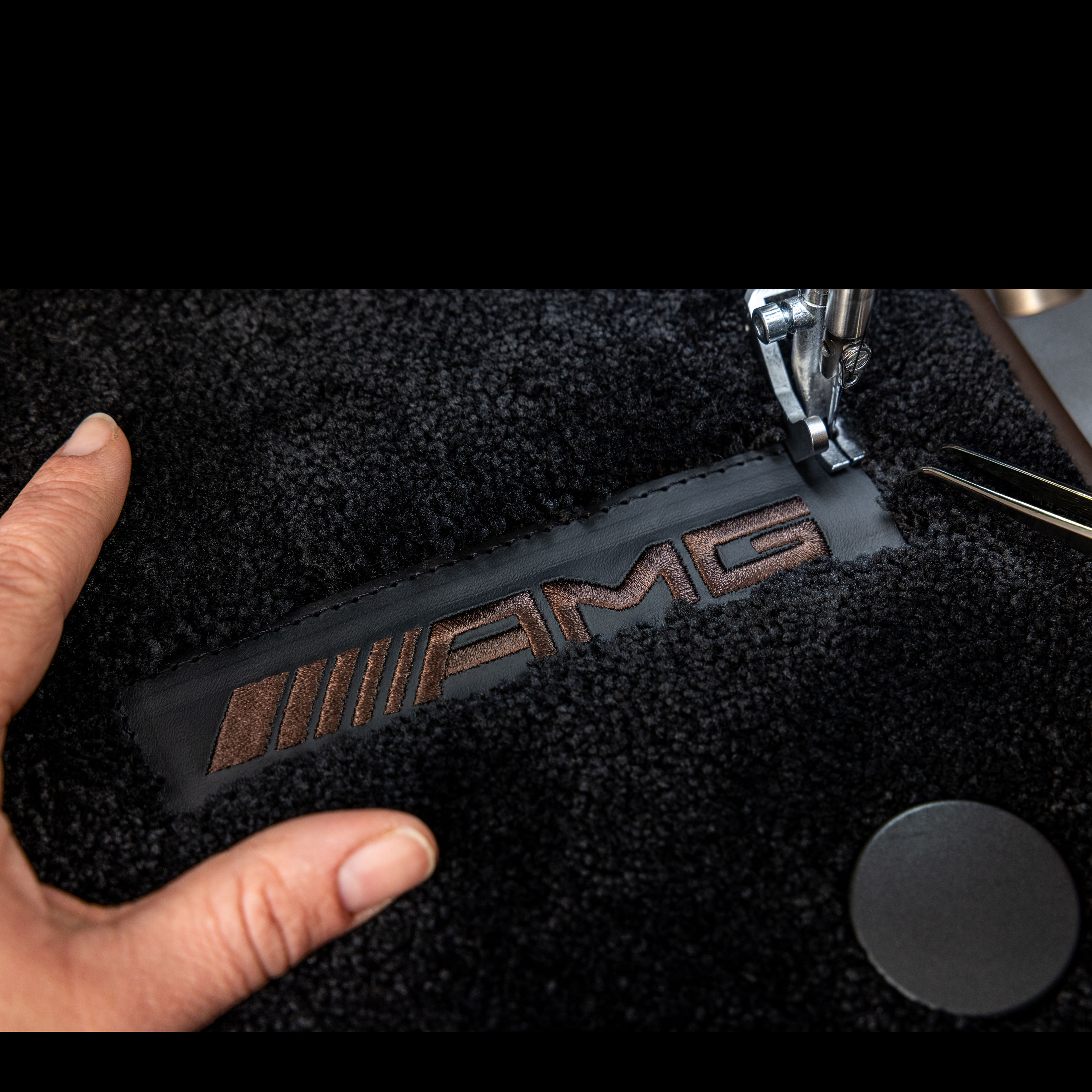 MANUFAKTUR | Mercedes-AMG Nápis MANUFAKTUR na tmavom povrchu vo vozidle Mercedes-AMG.