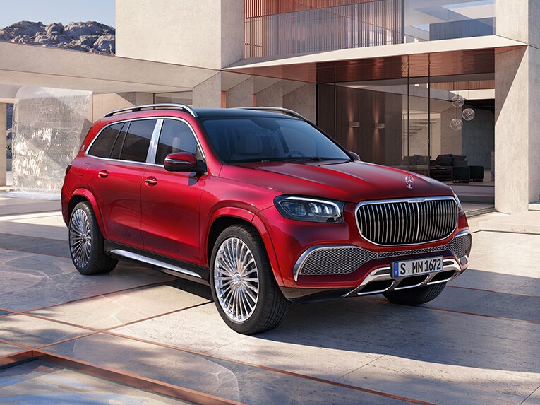 Bočný pohľad spredu na vozidlo Mercedes-Maybach GLS pred moderným domom.