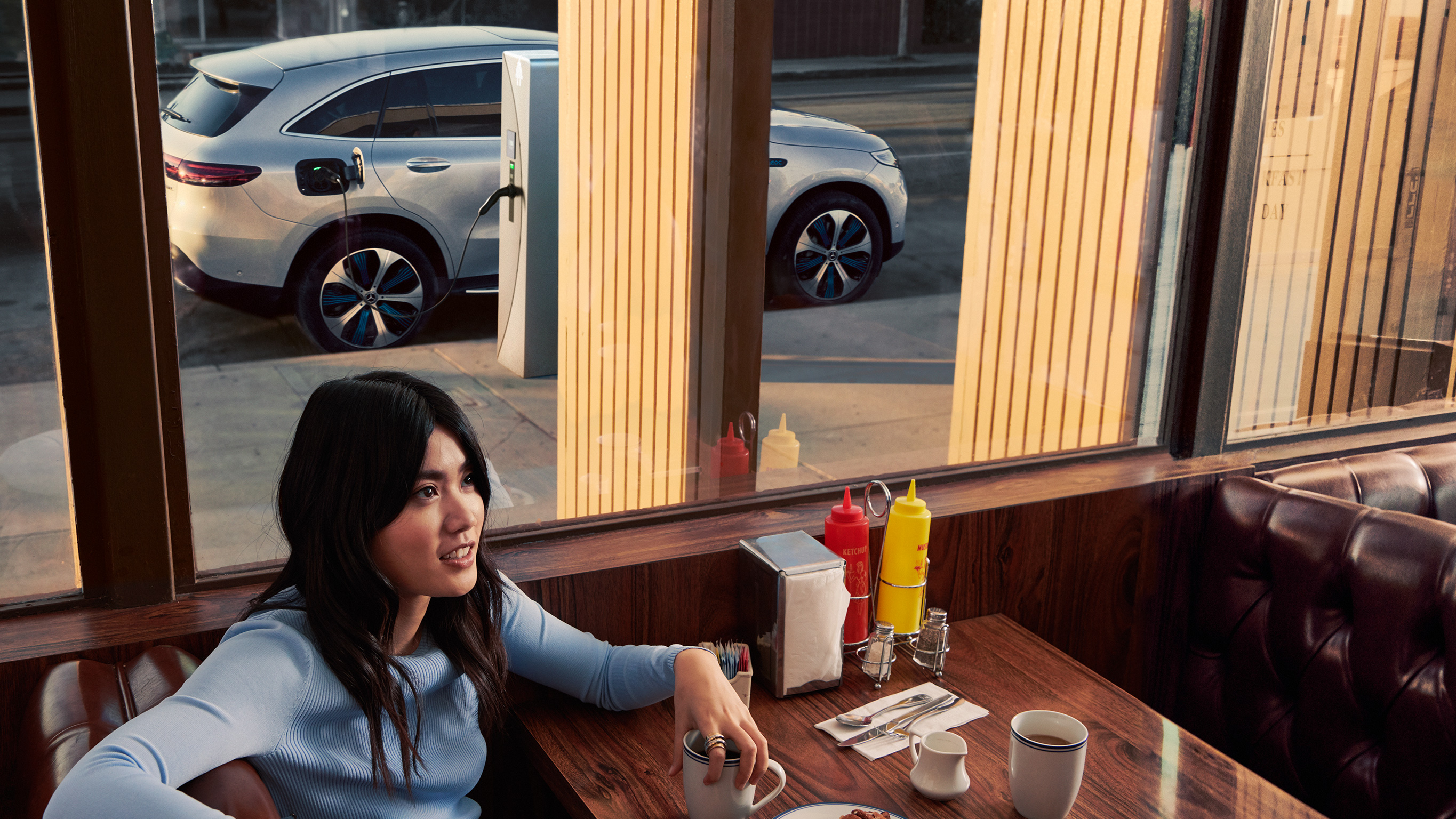 Mercedes-Benz Public Charging Človek čaká v reštaurácii, zatiaľ čo sa Mercedes-Benz nabíja