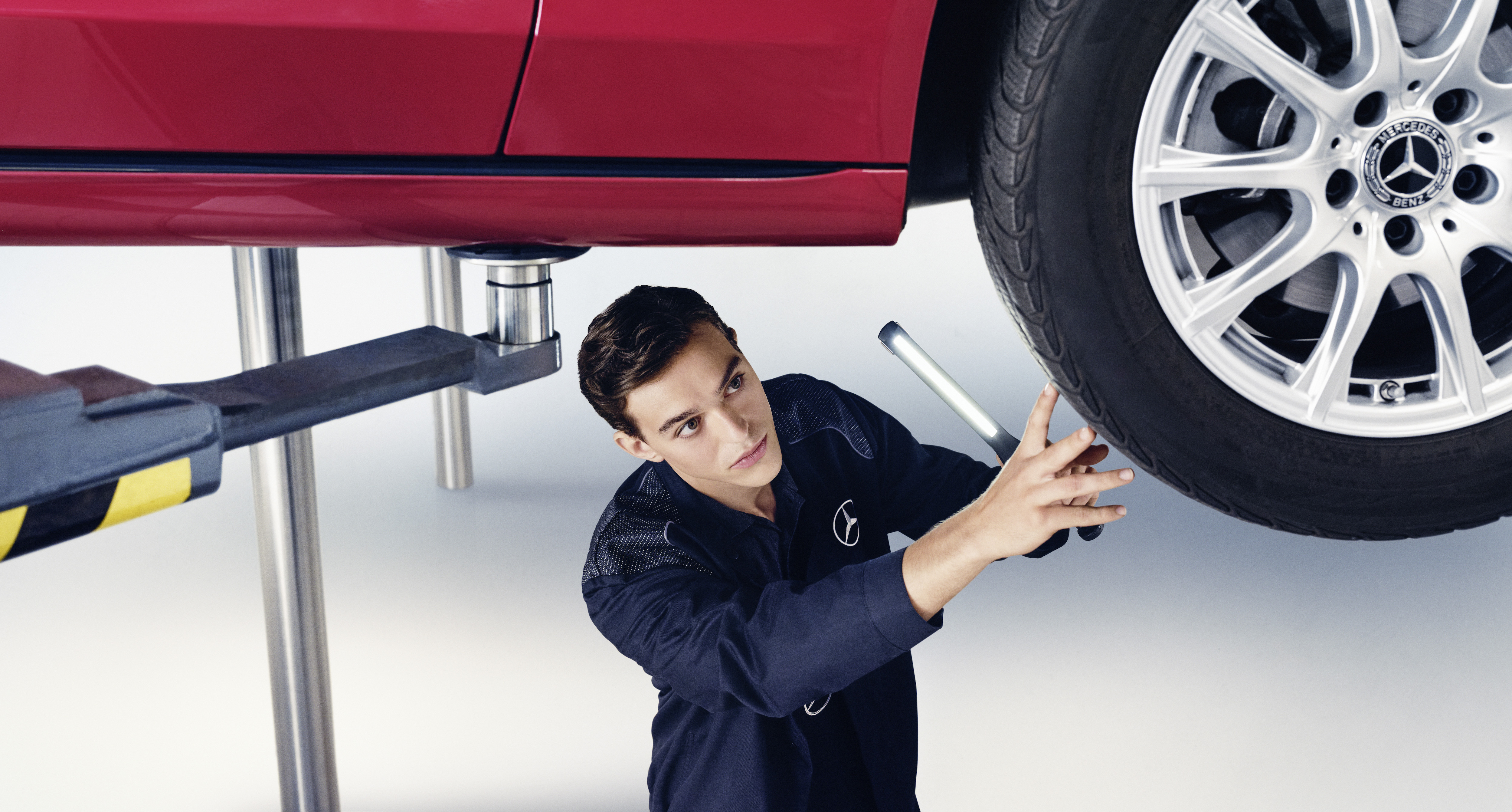Náhradné diely Mercedes-Benz Technik Mercedes-Benz kontroluje spodok vozidla.