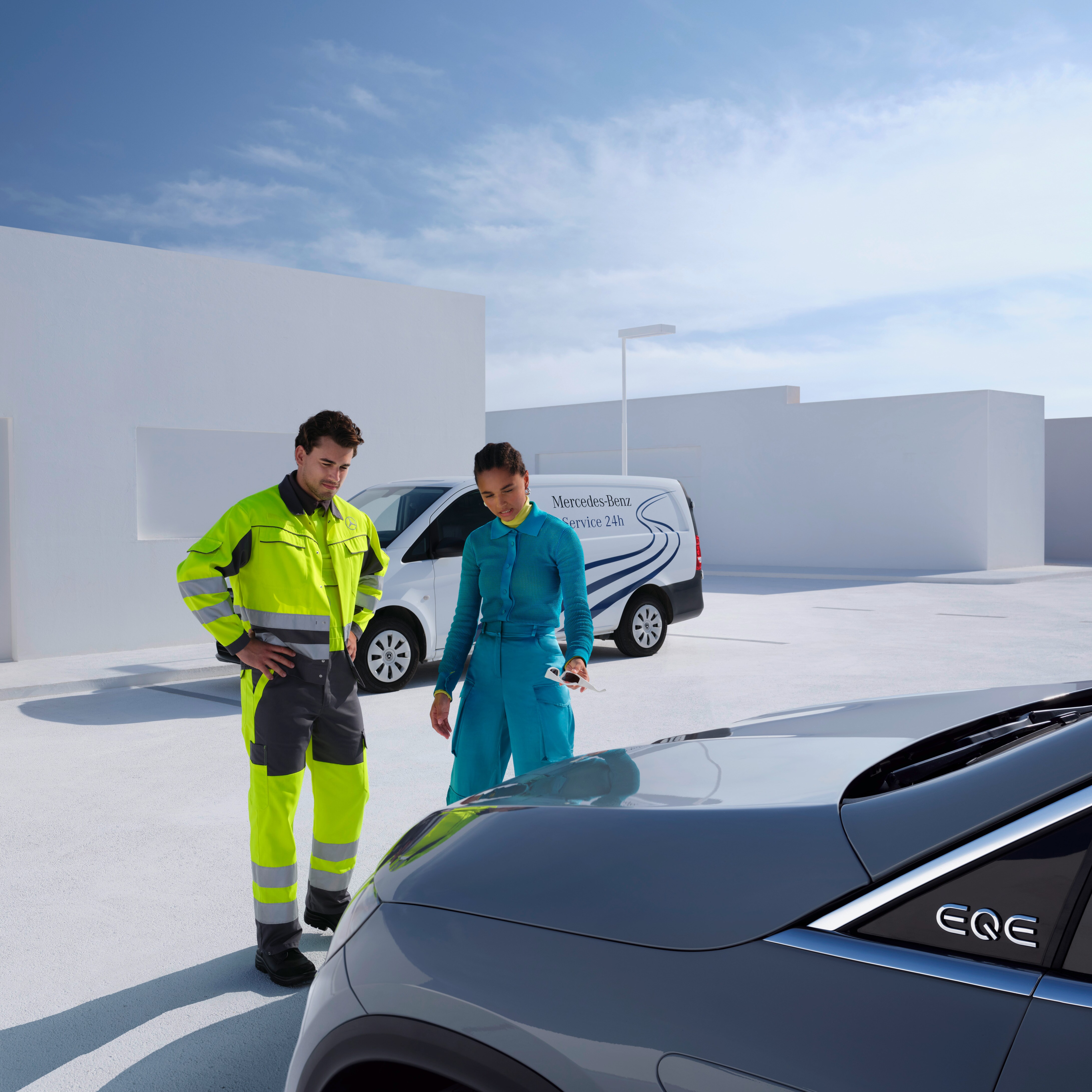 Muž zo servisného tímu Mercedes-Benz a žena sa pozerajú na vozidlo Mercedes-Benz