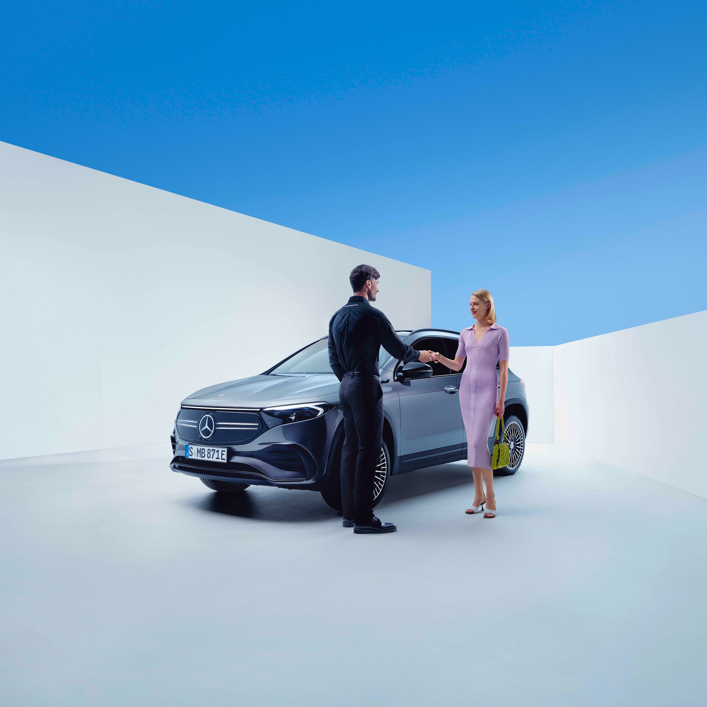 Zamestnanec spoločnosti Mercedes-Benz a žena si potriasajú rukami pred vozidlom Mercedes-Benz