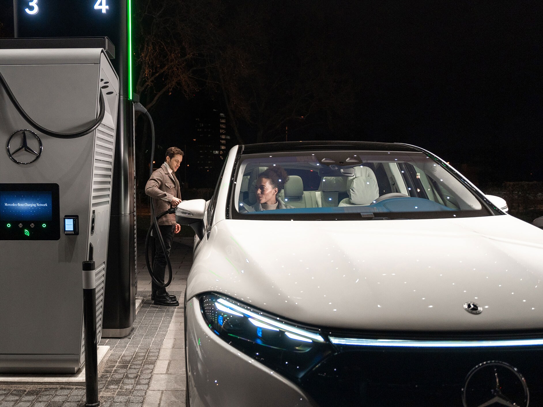 Osoba nabíja vozidlo Mercedes-Benz EQS SUV na nabíjacej stanici.