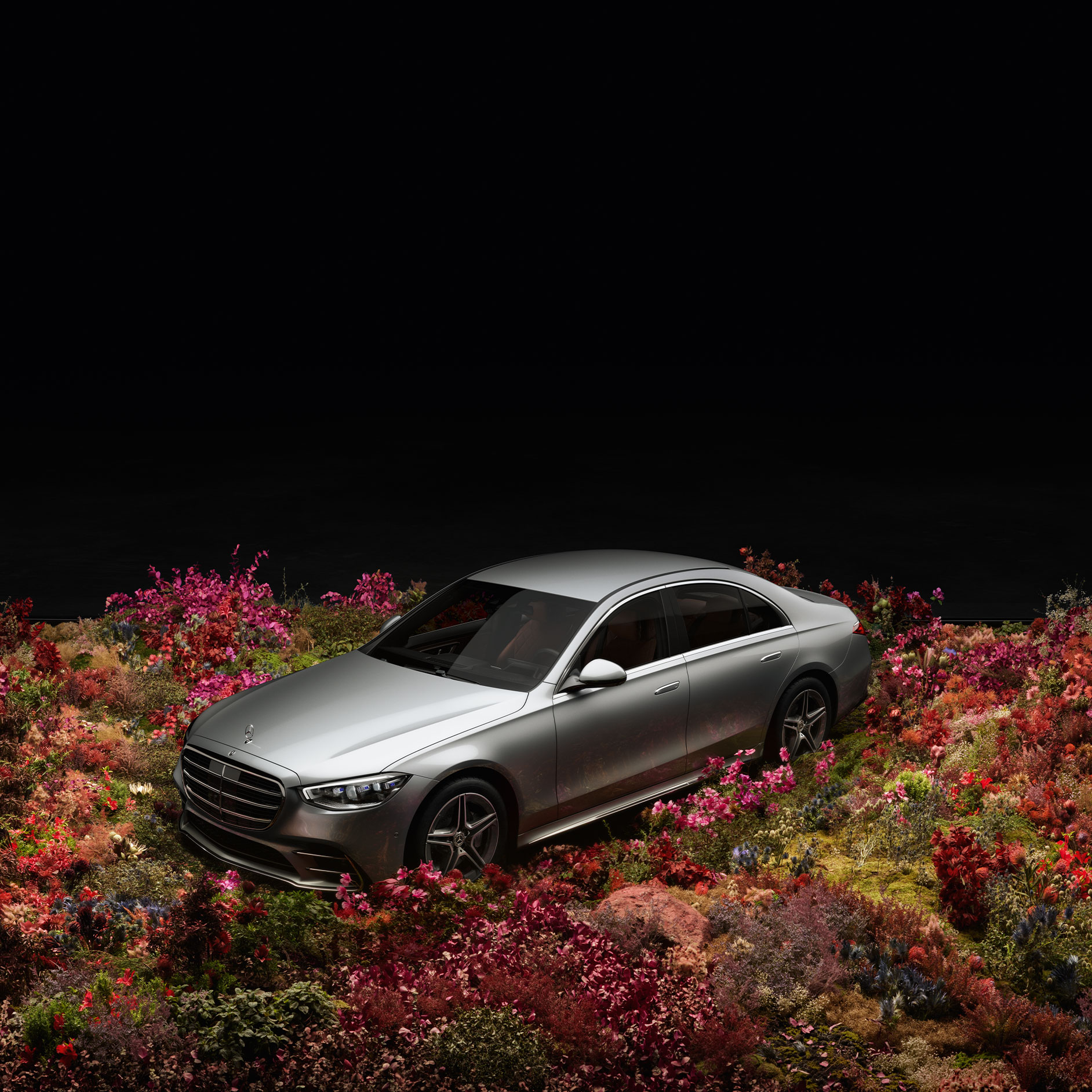 Technológie, ktoré vám rozumejú | Bezpečnosť | Mercedes-Benz Strieborný model Mercedes-Benz pred čiernym pozadím stojí na kvetinovom poli.