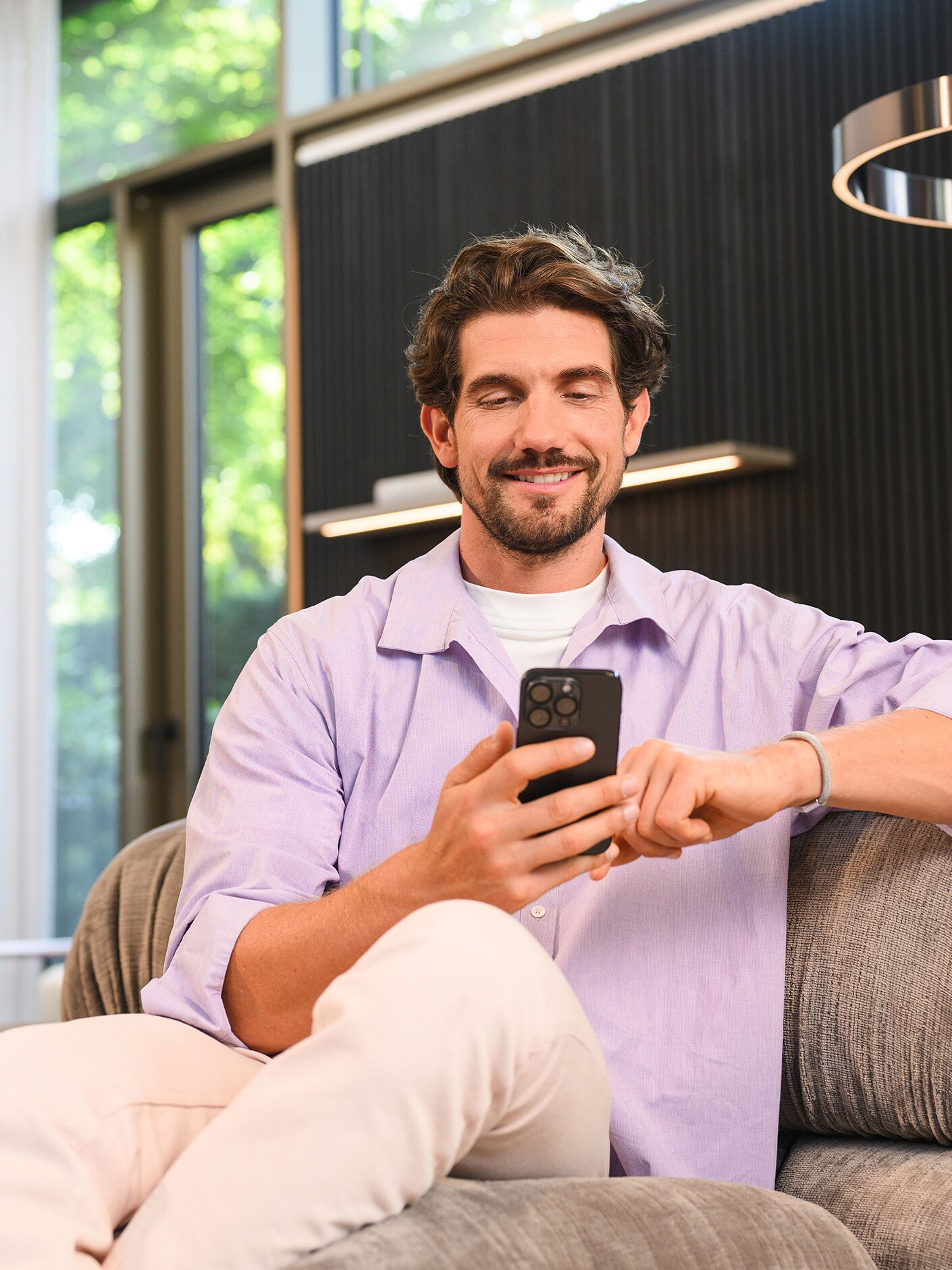 Osoba sediaca na pohovke a používajúca mobilné zariadenie.