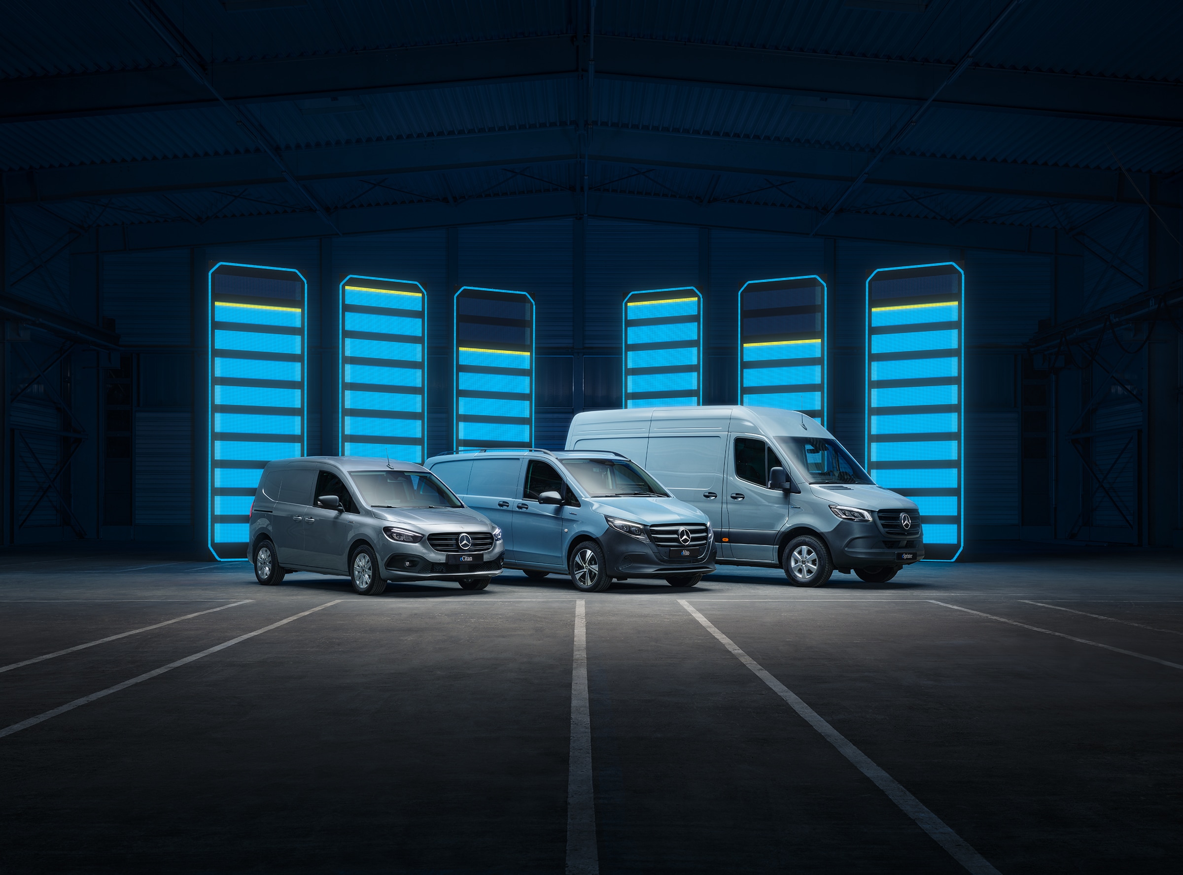 Modelový rad elektrických transportérov Mercedes-Benz | História úžitkových vozidiel | Mercedes-Benz Modelový rad elektrických transportérov Mercedes-Benz vystavený vo futuristickom sklade s osvetlenými nabíjacími lištami