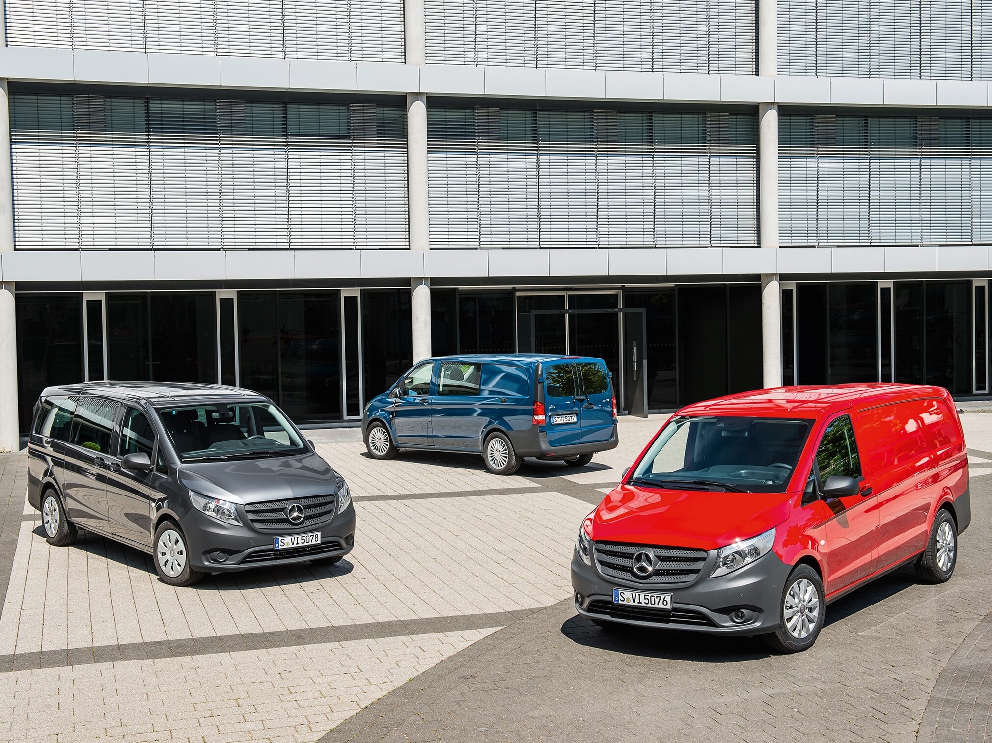 Niekoľko vozidiel Mercedes-Benz Vito zaparkovaných pred modernou administratívnou budovou