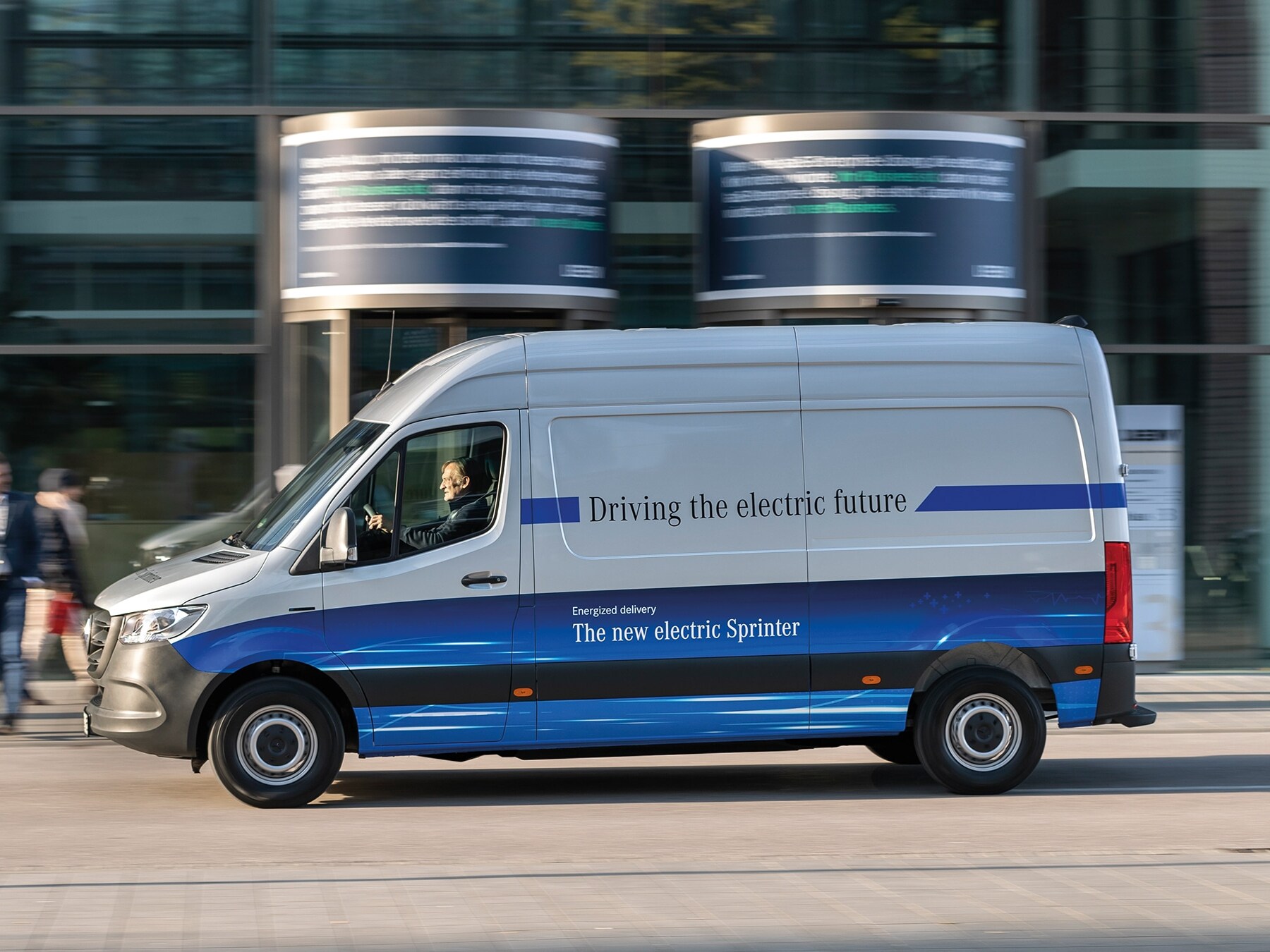 Skriňová dodávka Mercedes-Benz eSprinter jazdí po modernej mestskej ulici
