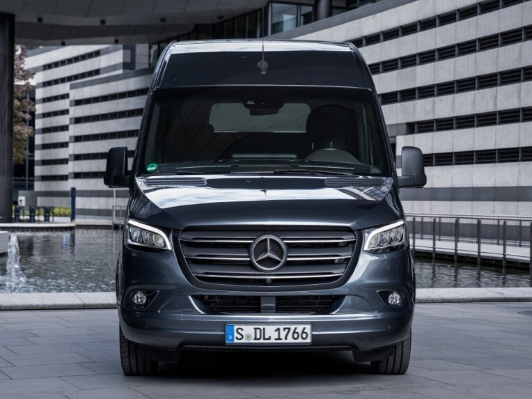 Pohľad spredu na skriňové vozidlo Sprinter od Mercedes-Benz, ktoré stojí v mestskom prostredí.
