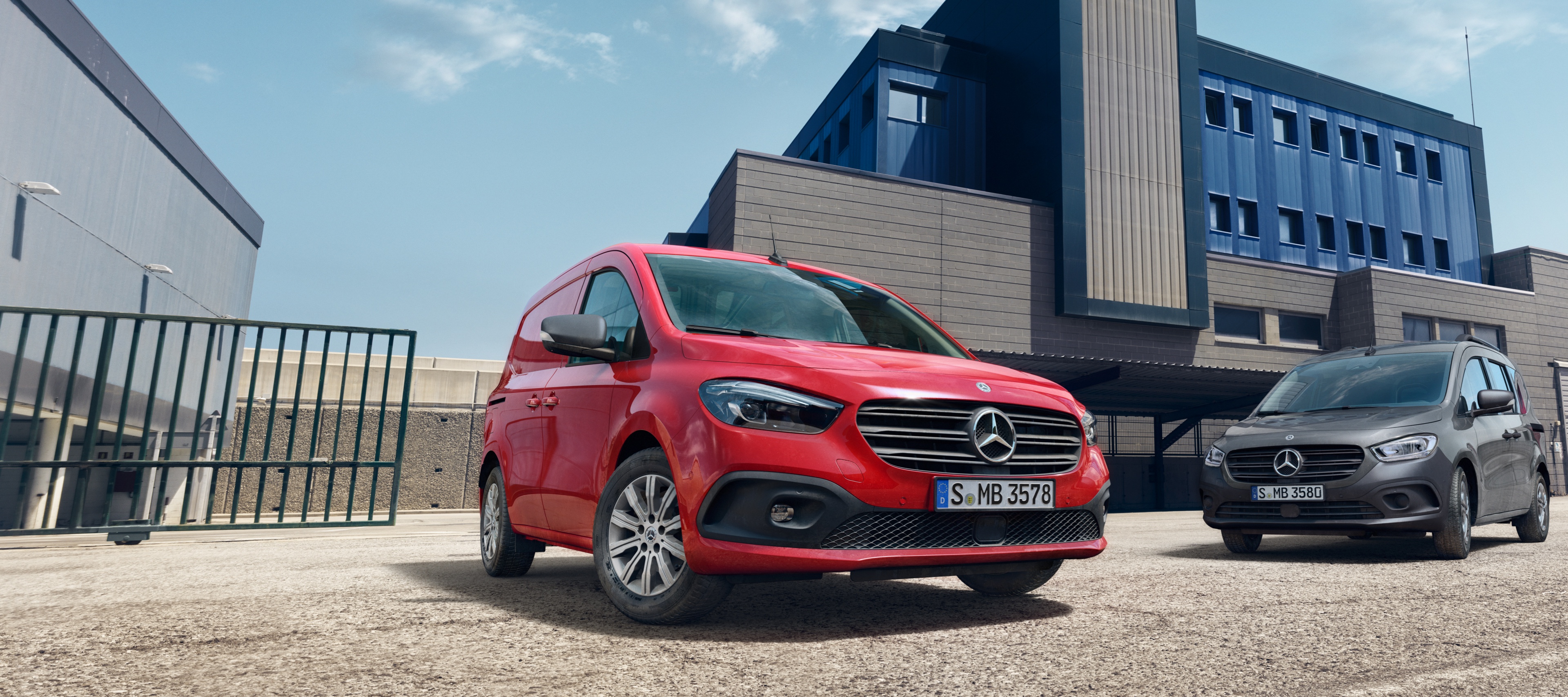 Citan | Úžitkové vozidlá Mercedes-Benz Mercedes-Benz eCitan ako Tourer a skriňové vozidlo stoja pred priemyselným areálom.