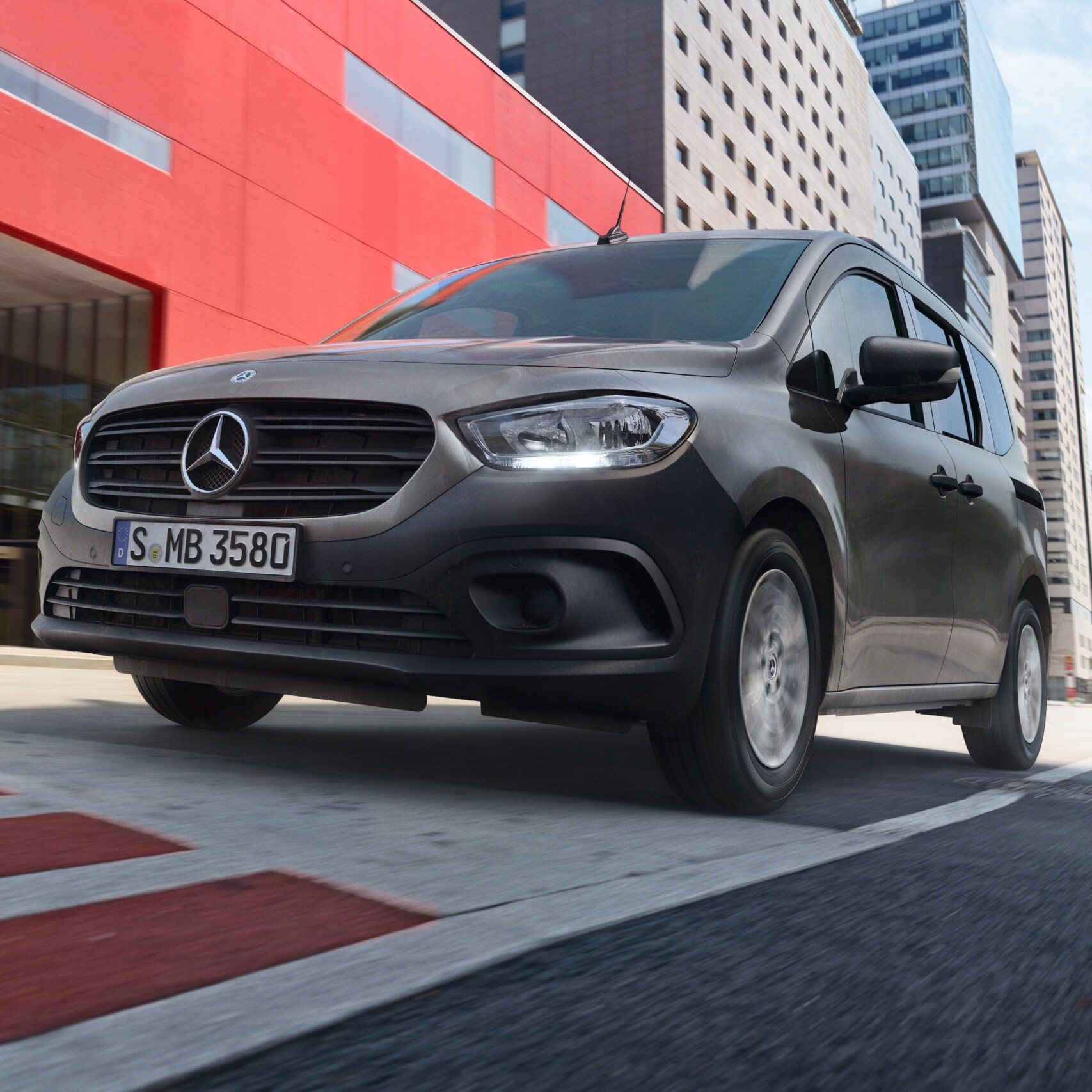 Citan Tourer, kompaktný transportér na prepravu osôb od značky Mercedes-Benz, počas jazdy cez modernú mestskú oblasť.
