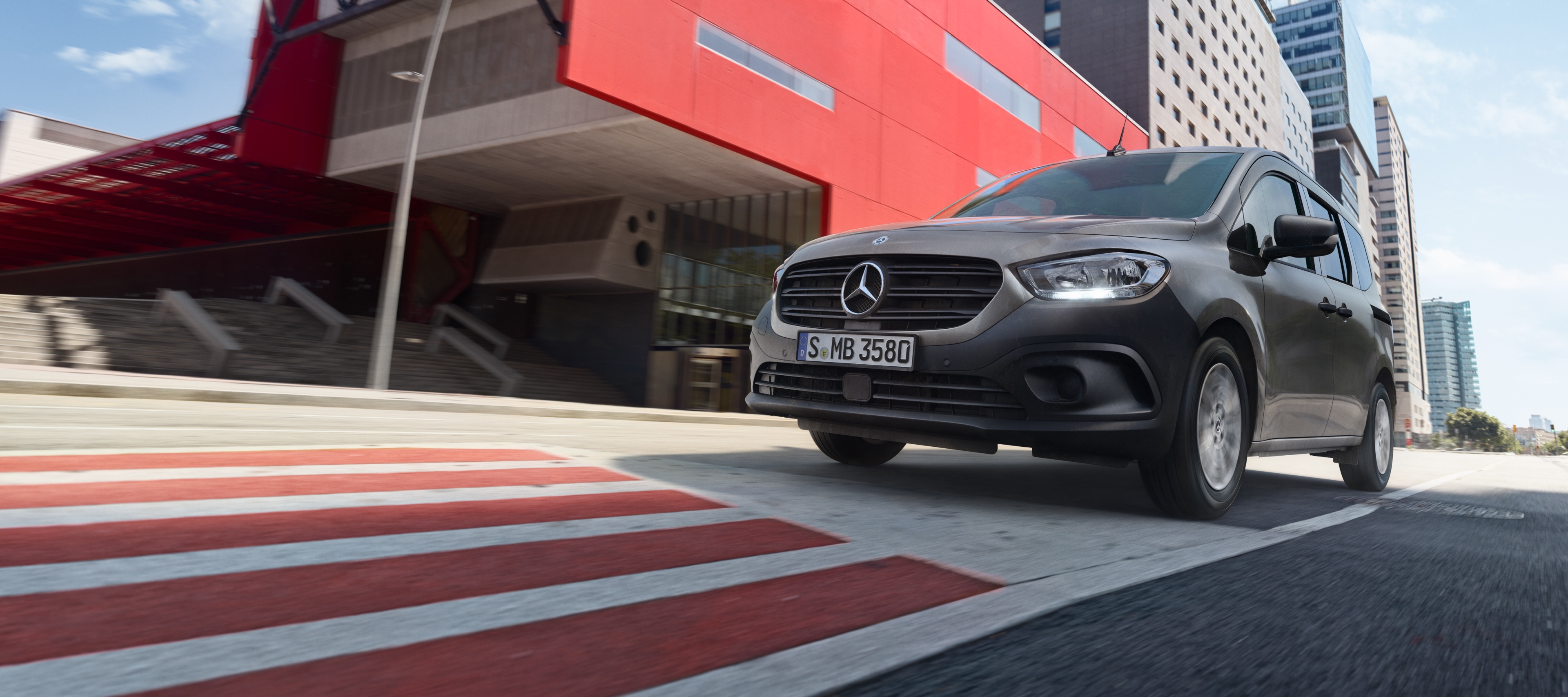 Citan Tourer | Transportéry Mercedes-Benz Citan Tourer, kompaktný transportér na prepravu osôb od značky Mercedes-Benz, počas jazdy cez modernú mestskú oblasť.