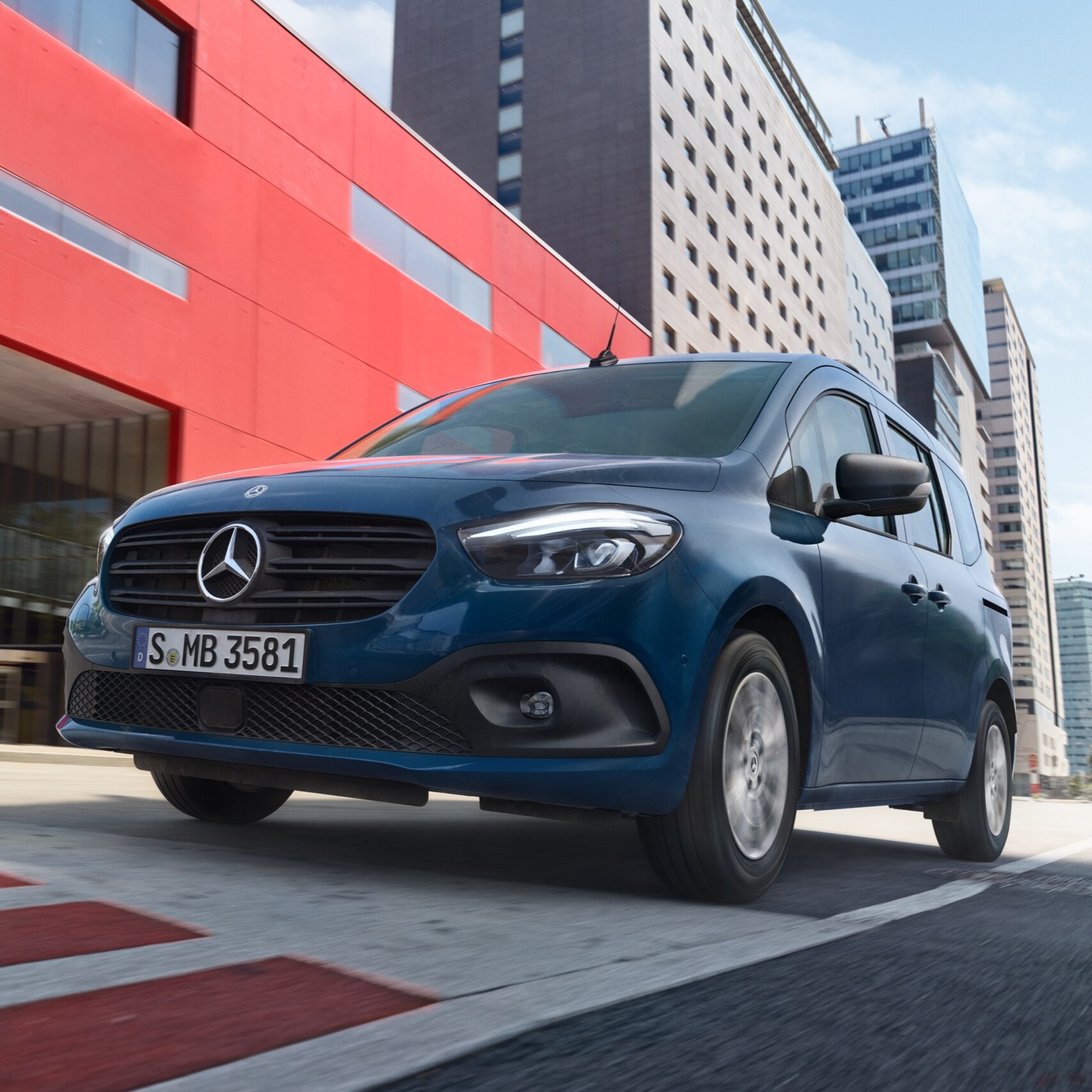eCitan Tourer, elektrický transportér na prepravu osôb od značky Mercedes-Benz, počas jazdy cez modernú mestskú oblasť.