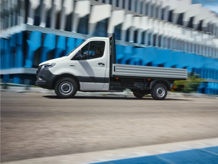 Šasi Mercedes-Benz eSprinter ako valník prechádzajúce okolo budovy.
