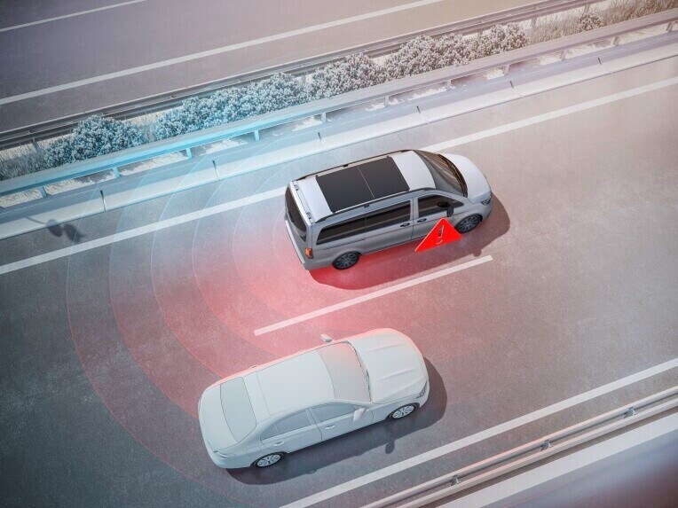 Dve vozidlá idúce po diaľnici počas predbiehania vozidla Vito Tourer v susediacom jazdnom pruhu. Na vonkajšom zrkadle svieti červený výstražný trojuholník, ktorý upozorňuje na vozidlo v mŕtvom uhle.