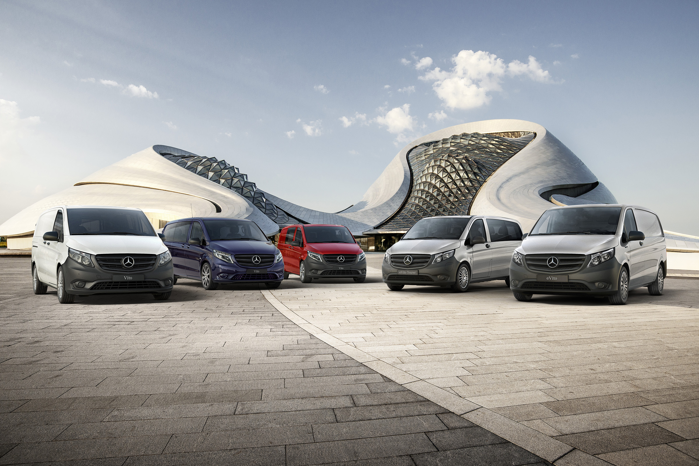 Dojazd vozidla Vito | Všetky vozidlá Vito | Transportéry Mercedes-Benz Skriňové vozidlá Mercedes-Benz eVito a Vito a vozidlá Vito Mixto, eVito Tourer a Vito Tourer stoja veľa seba pred futuristickou budovou