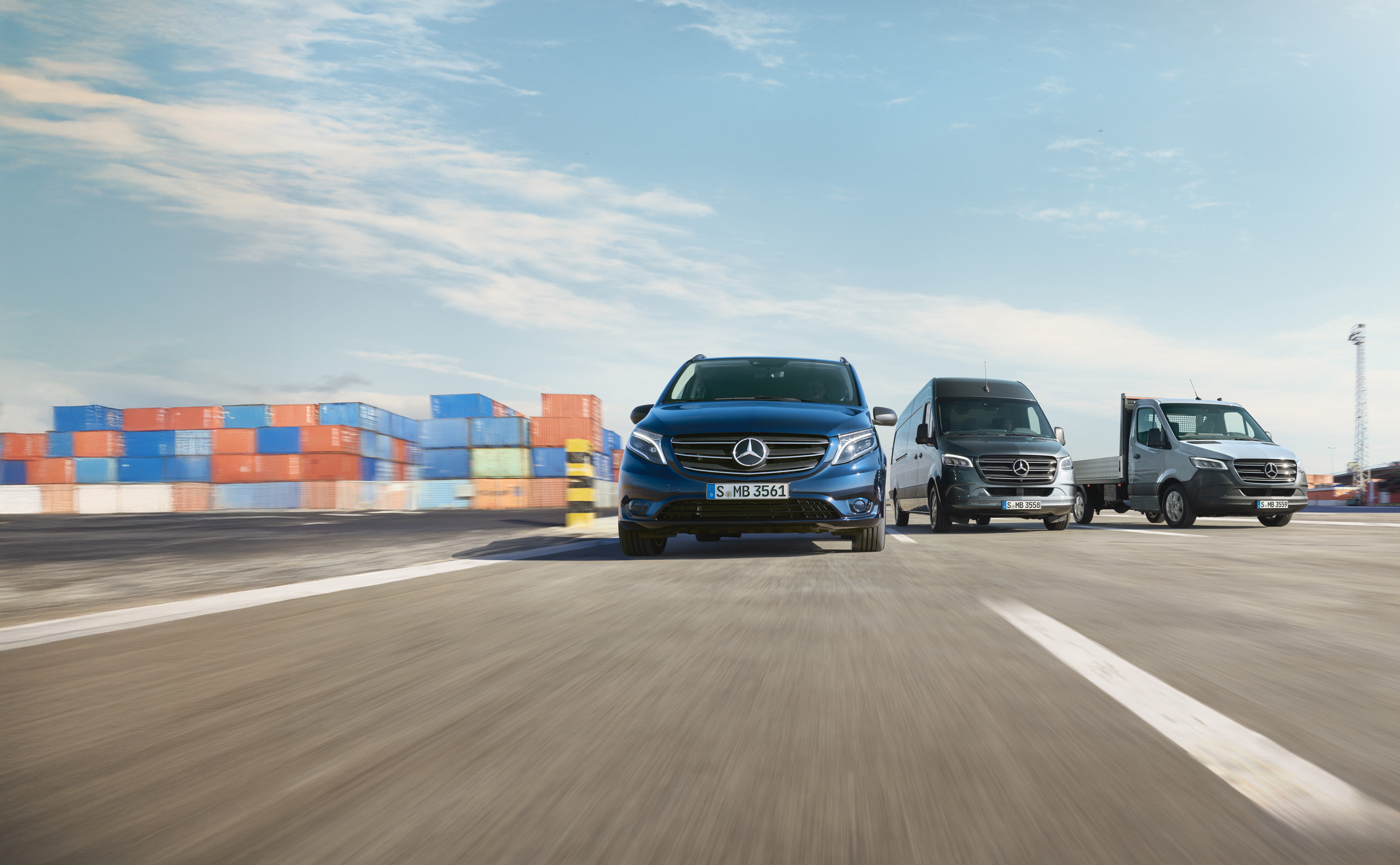 Mercedes-Benz | Starostlivosť o dodávky | Služba24h Niekoľko úžitkových vozidiel Mercedes-Benz zaparkovaných vedľa seba na ceste vedľa nakladacej rampy.