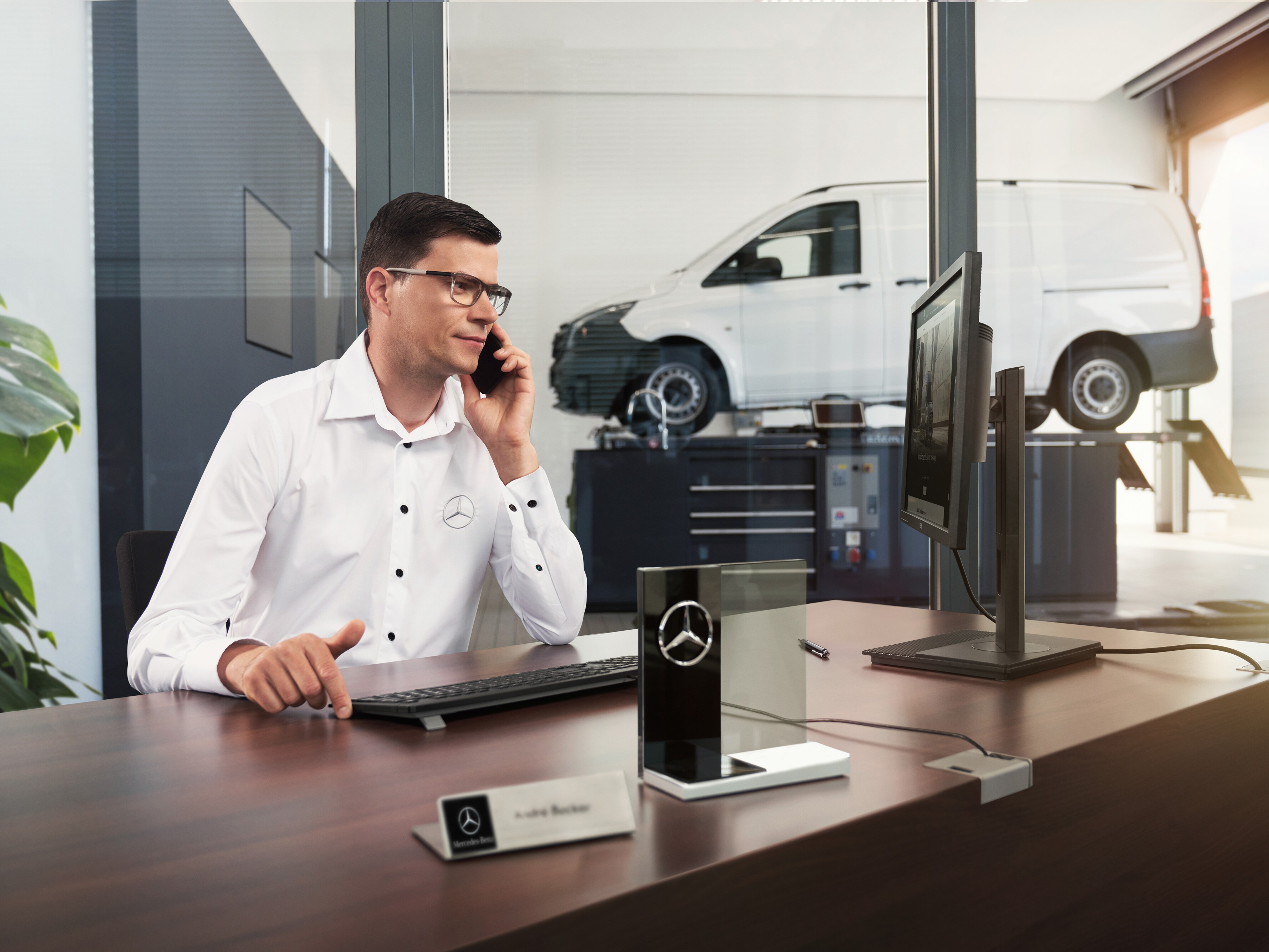 Servisný poradca Mercedes-Benz telefonuje v&nbsp;dielni.