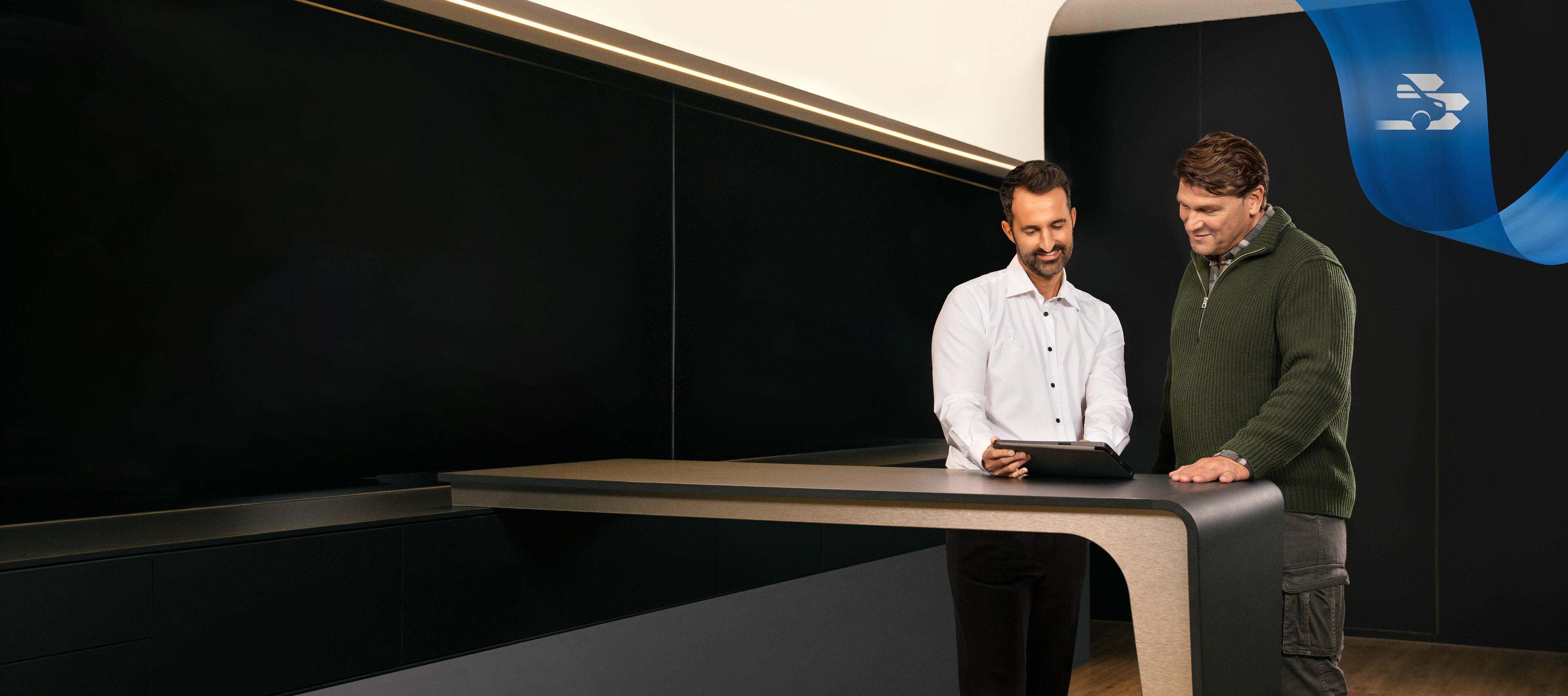 Mercedes-Benz | Pohodlie | Servisný partner Dvaja muži stojaci v kancelárii servisného partnera Mercedes-Benz sa rozprávajú a pozerajú sa na tablet