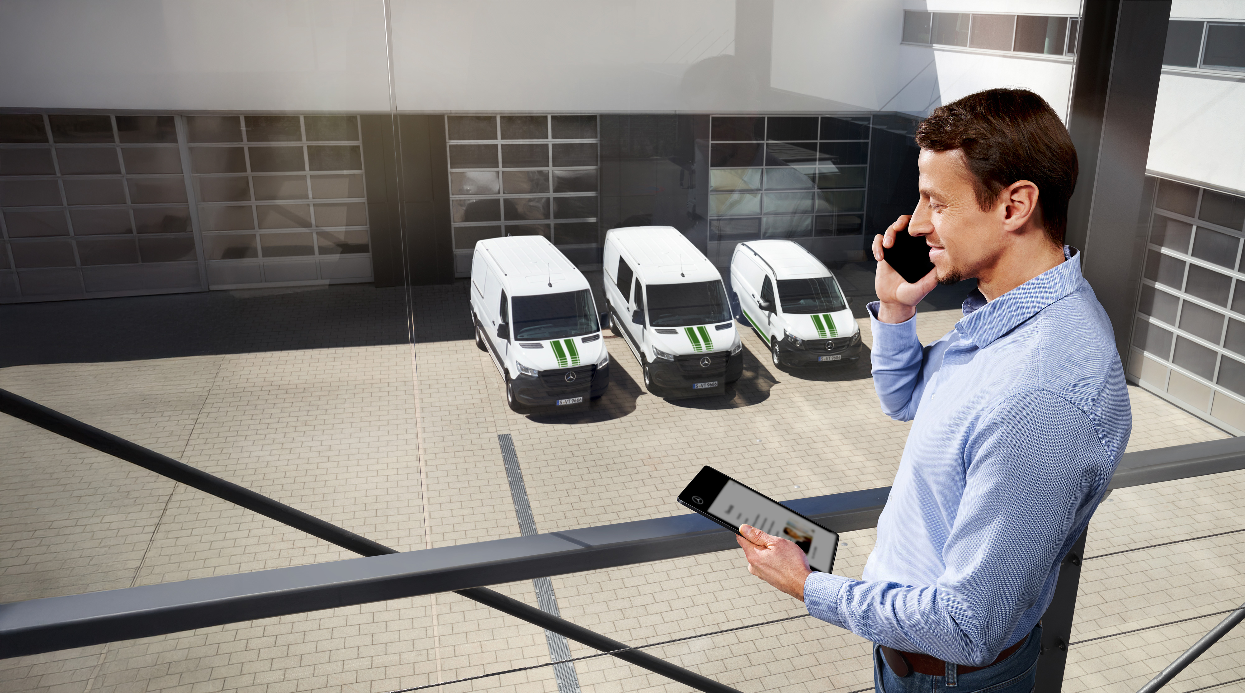 Mercedes-Benz | Záruka kvality úžitkových vozidiel Muž telefonuje s tabletom pred tromi úžitkovými vozidlami Mercedes-Benz, téma: ako dlho trvá záruka výrobcu u Mercedes-Benz?