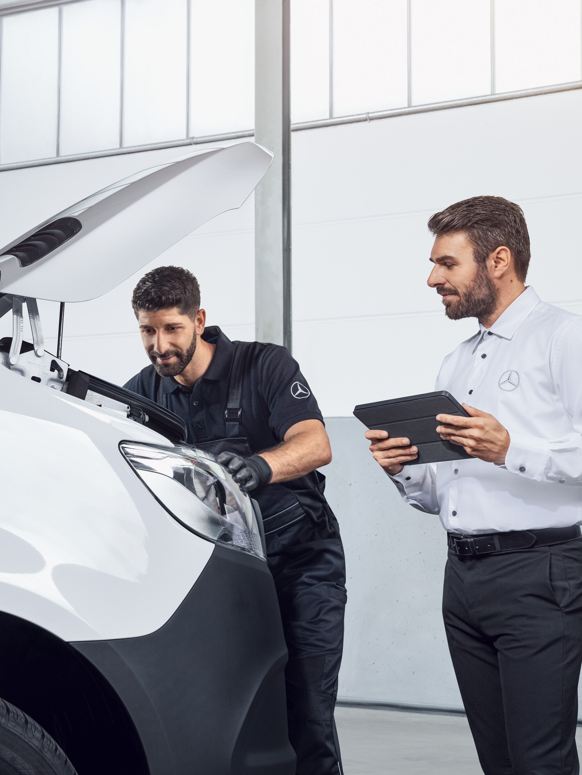 Dvaja muži testujú vozidlo Mercedes Sprinter s&nbsp;tabletom a&nbsp;otvorenou kapotou motora, téma: náhradné diely pre vozidlo Mercedes-Benz Sprinter.