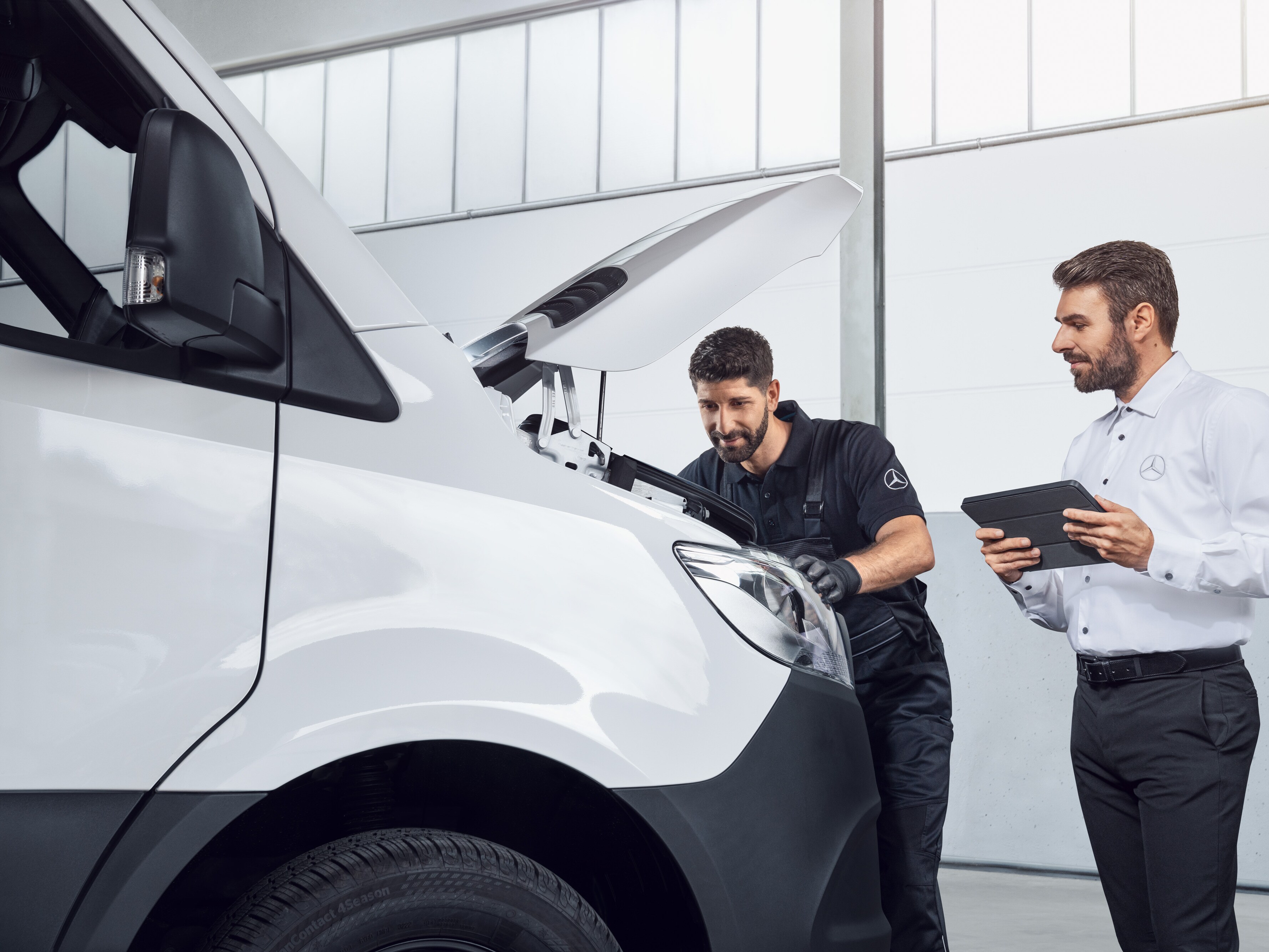 Dvaja muži testujú vozidlo Mercedes Sprinter s&nbsp;tabletom a&nbsp;otvorenou kapotou motora, téma: náhradné diely pre vozidlo Mercedes-Benz Sprinter.