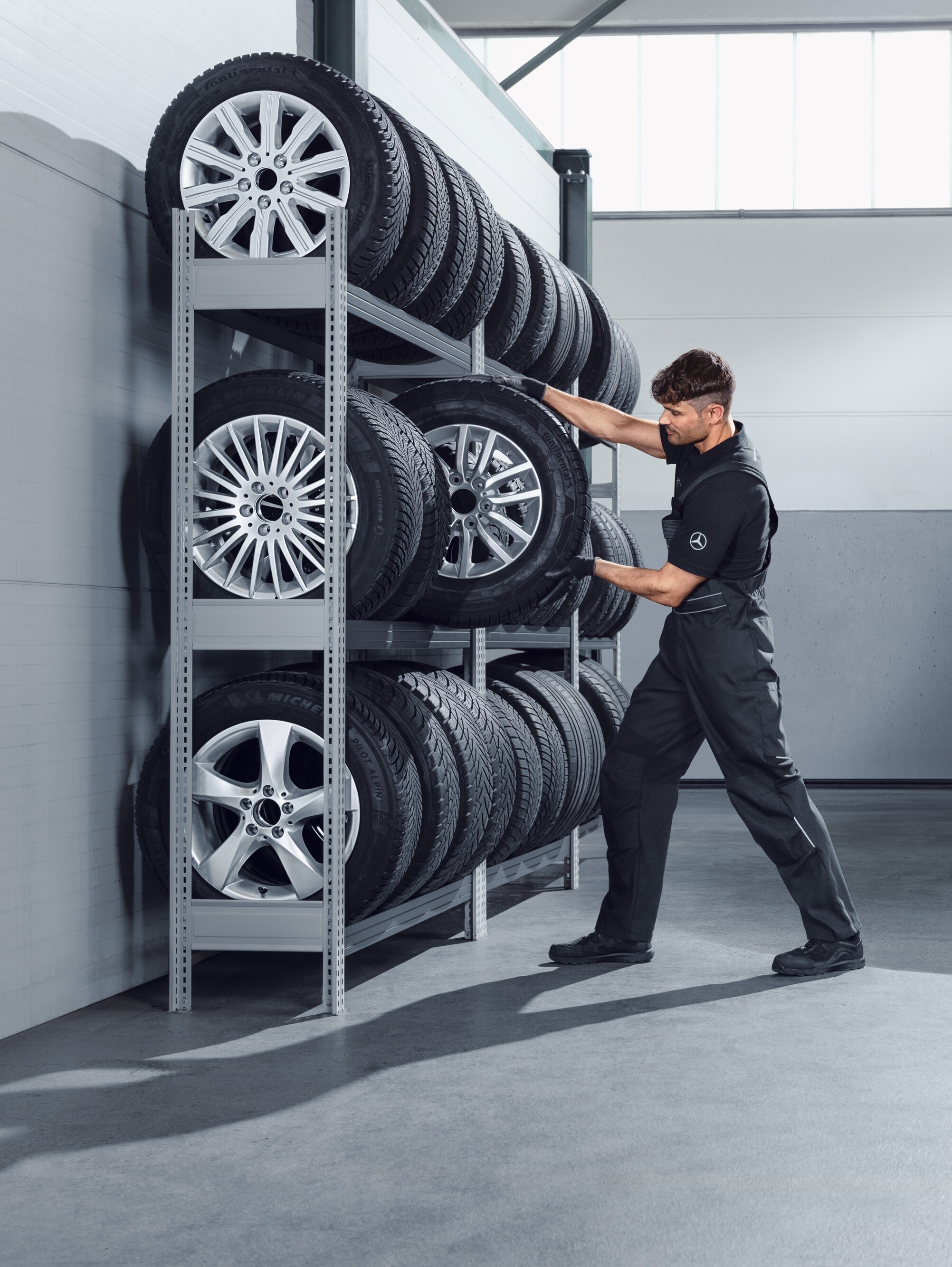 Mechanik vyberá z&nbsp;dielenskej police kompletné zimné kolesá Mercedes-Benz pre biele vozidlo Sprinter.