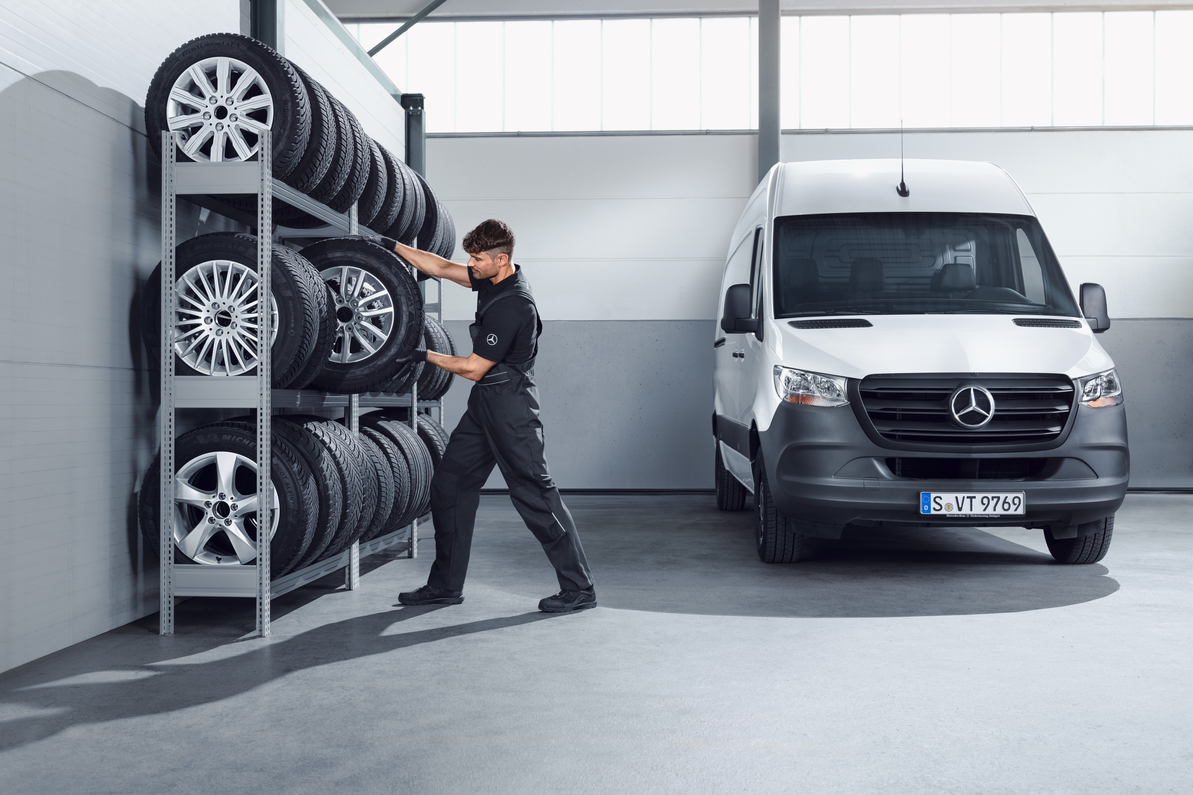 Mercedes-Benz | Kvalita originálnych dielov pre úžitkové vozidlá Mechanik vyberá z dielenskej police kompletné zimné kolesá Mercedes-Benz pre biele vozidlo Sprinter.