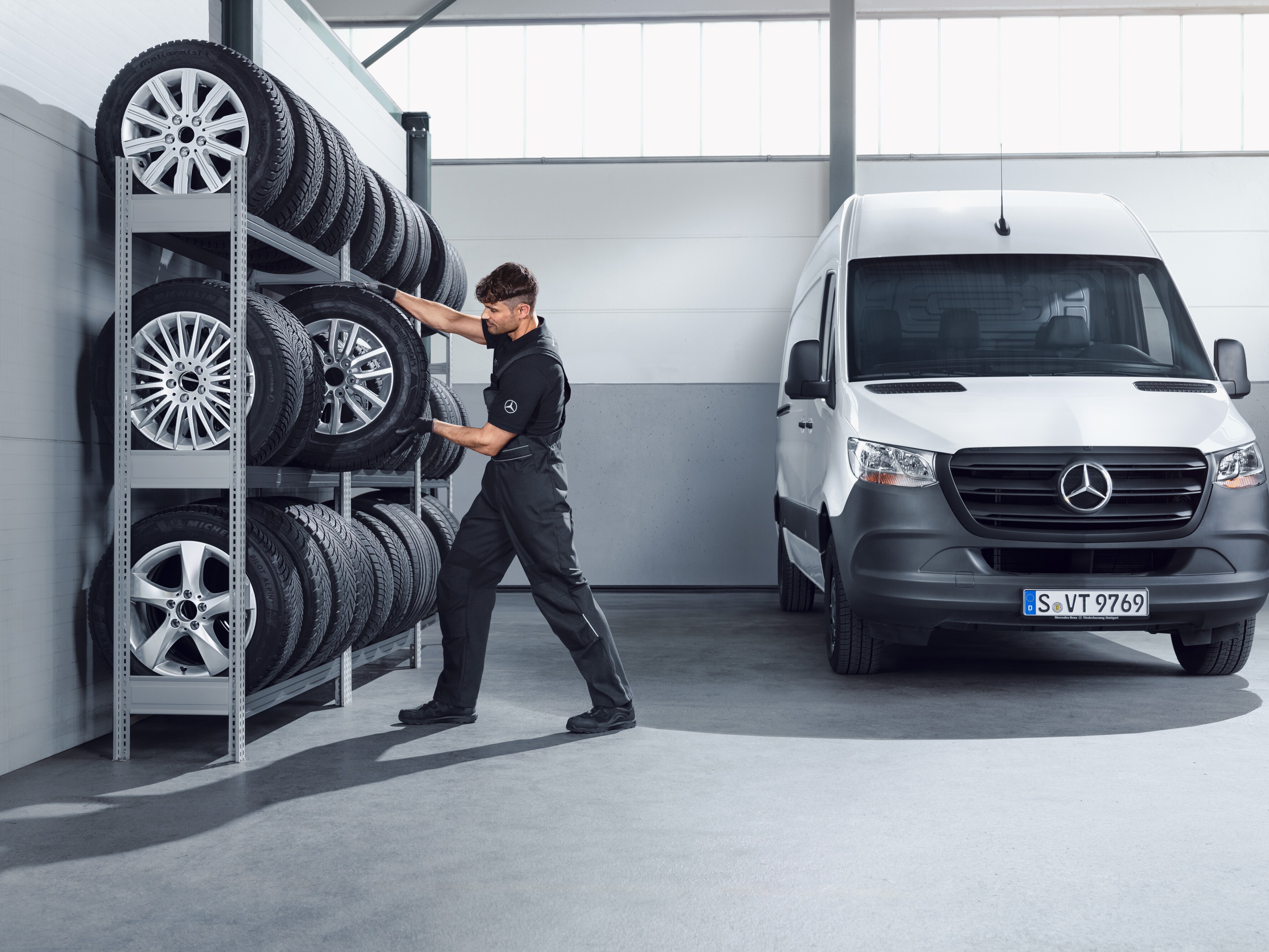 Mechanik vyberá z&nbsp;dielenskej police kompletné zimné kolesá Mercedes-Benz pre biele vozidlo Sprinter.