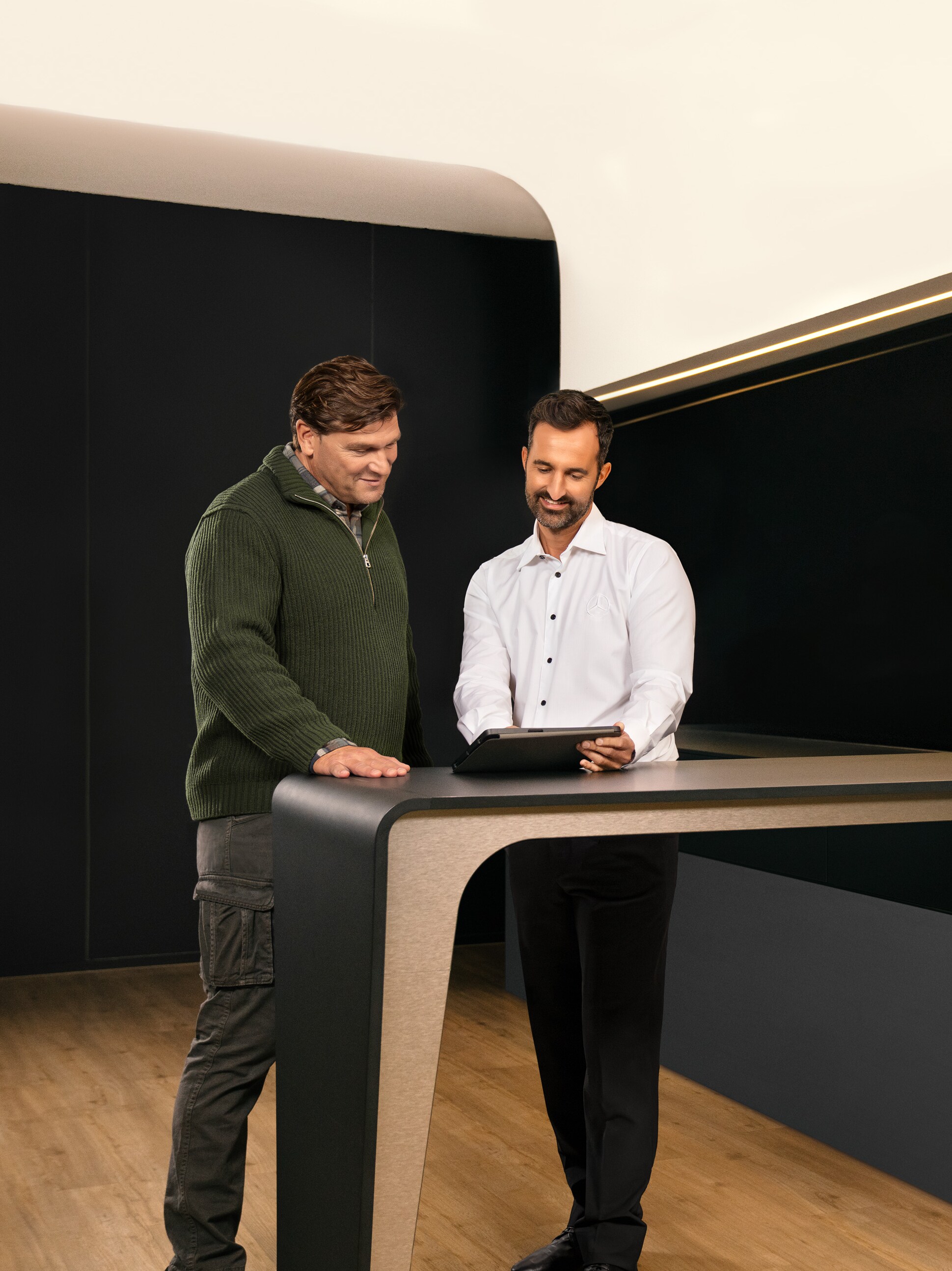 Dvaja muži diskutujú nad tabletom o&nbsp;servise úžitkových vozidiel od značky Mercedes-Benz.