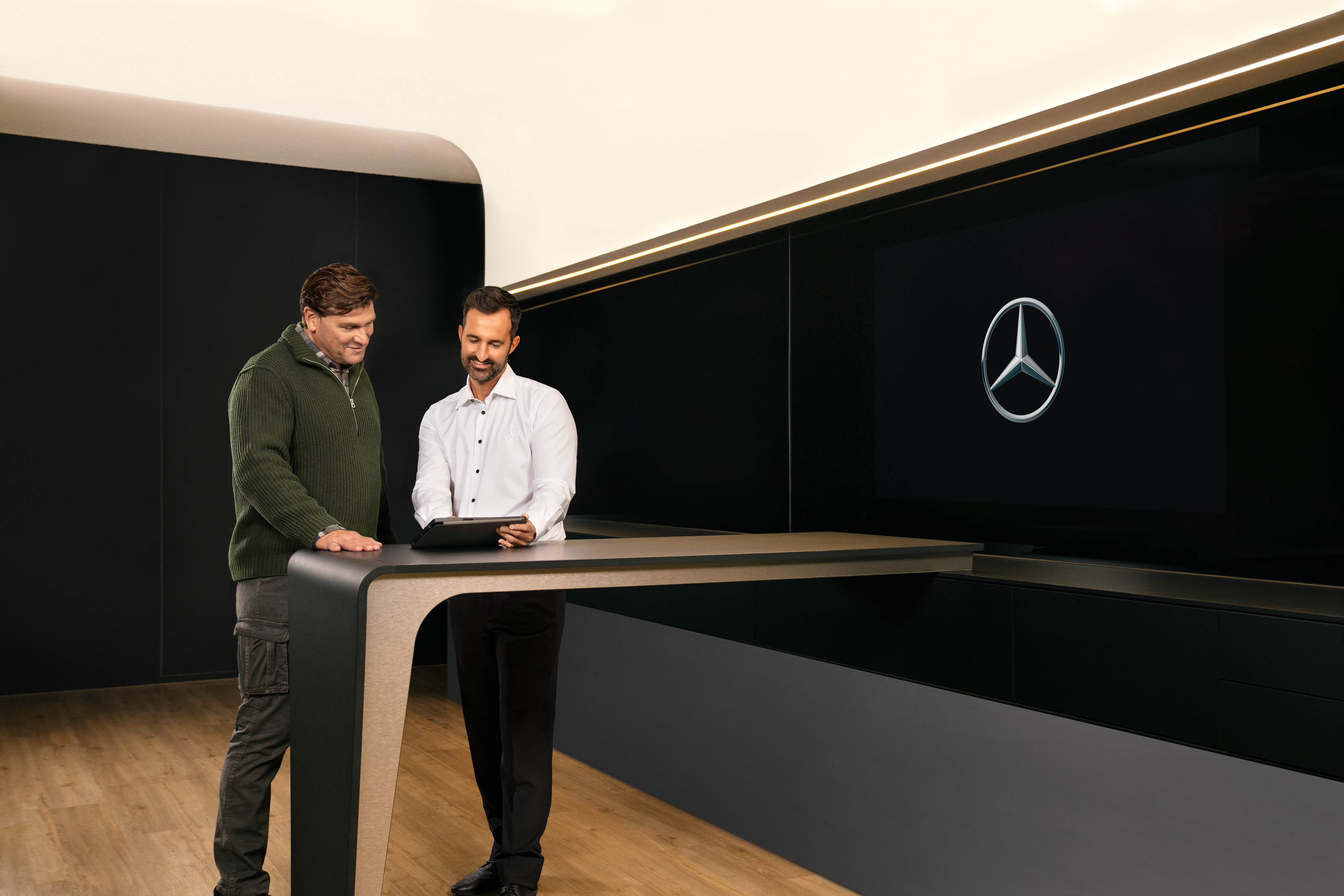 Mercedes-Benz | Prehľad služieb | ServiceCare Dvaja muži diskutujú nad tabletom o servise úžitkových vozidiel od značky Mercedes-Benz.