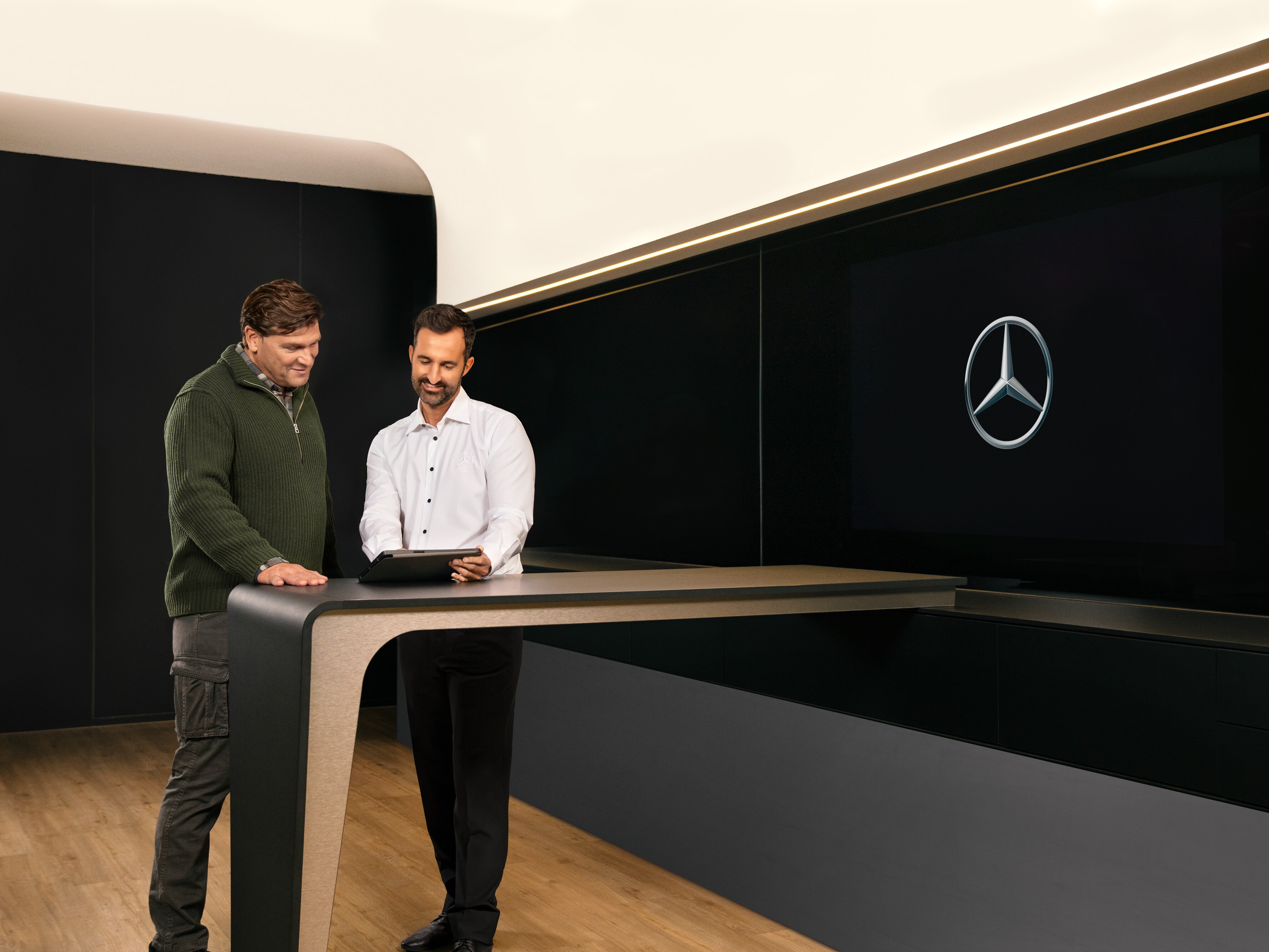 Dvaja muži diskutujú nad tabletom o&nbsp;servise úžitkových vozidiel od značky Mercedes-Benz.