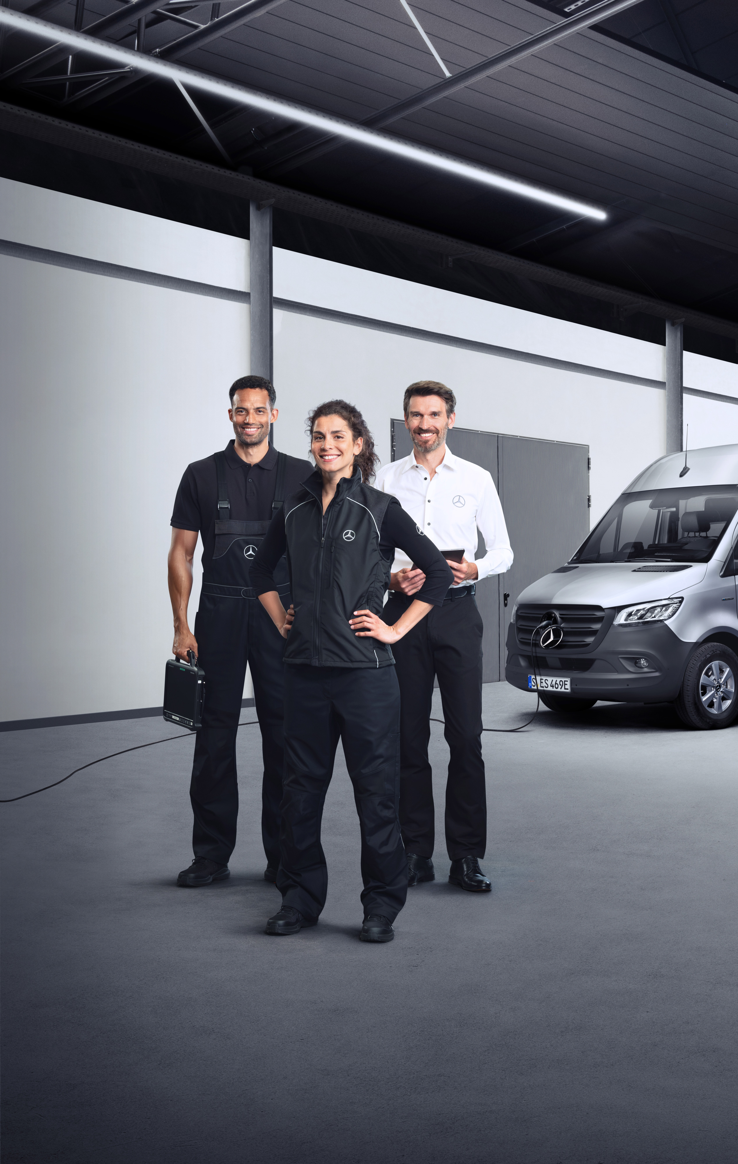 Mercedes-Benz | Prehľad služieb | Služby pre elektrické transportéry Traja zamestnanci stoja pred strieborným vozidlom Mercedes-Benz eSprinter so zapojeným nabíjacím káblom.