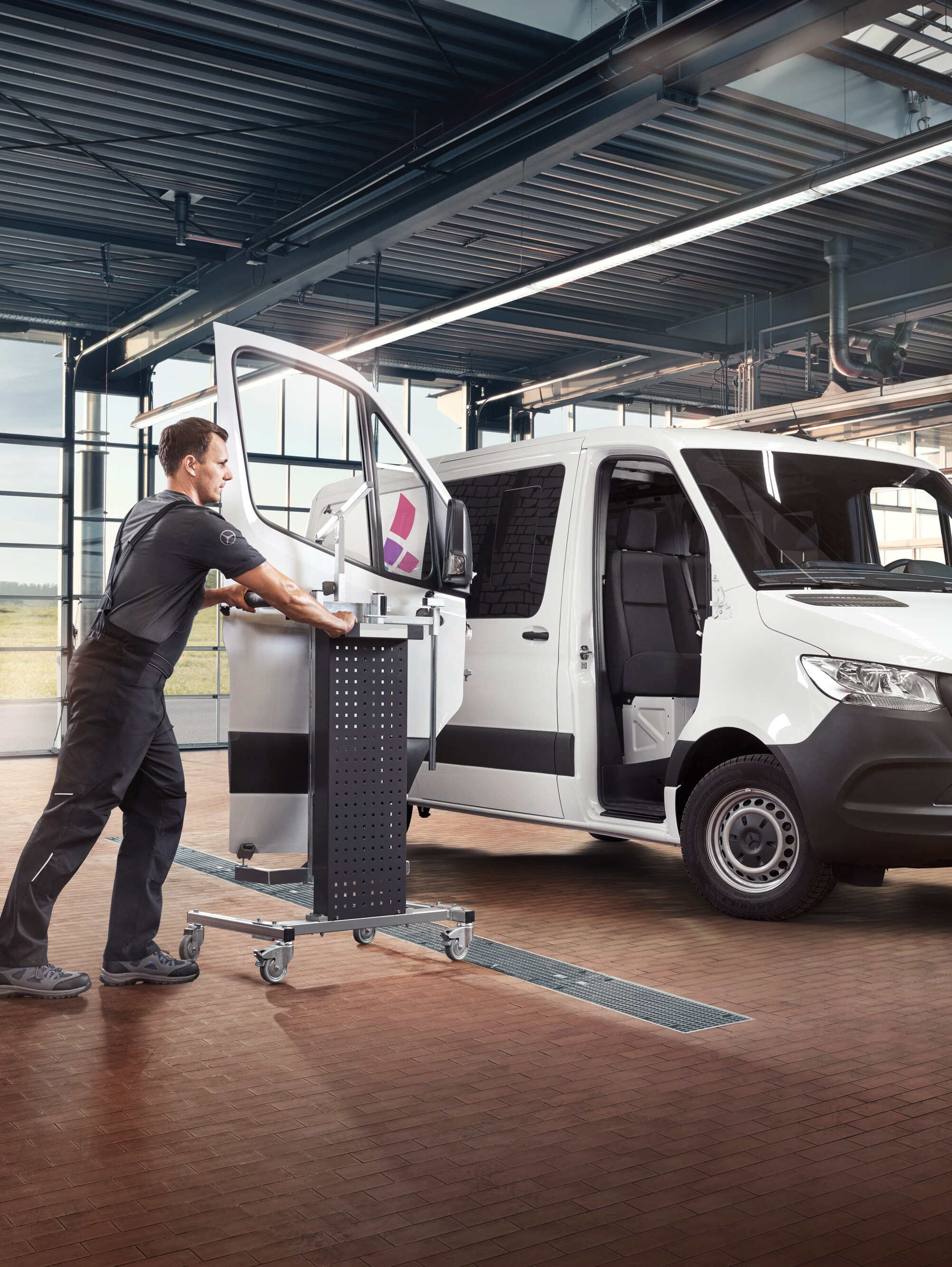 Technik vykonáva údržbu dverí spolujazdca na bielom úžitkovom vozidle Mercedes-Benz Sprinter.