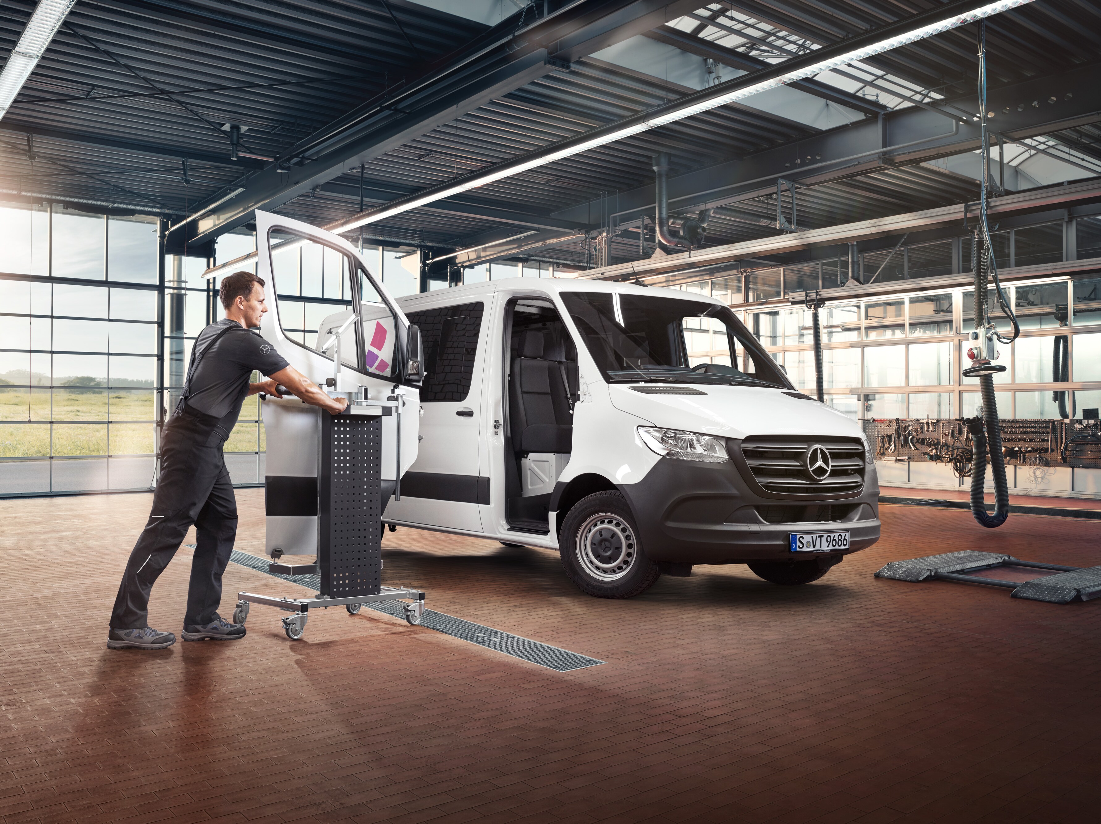 Technik vykonáva údržbu dverí spolujazdca na bielom úžitkovom vozidle Mercedes-Benz Sprinter.