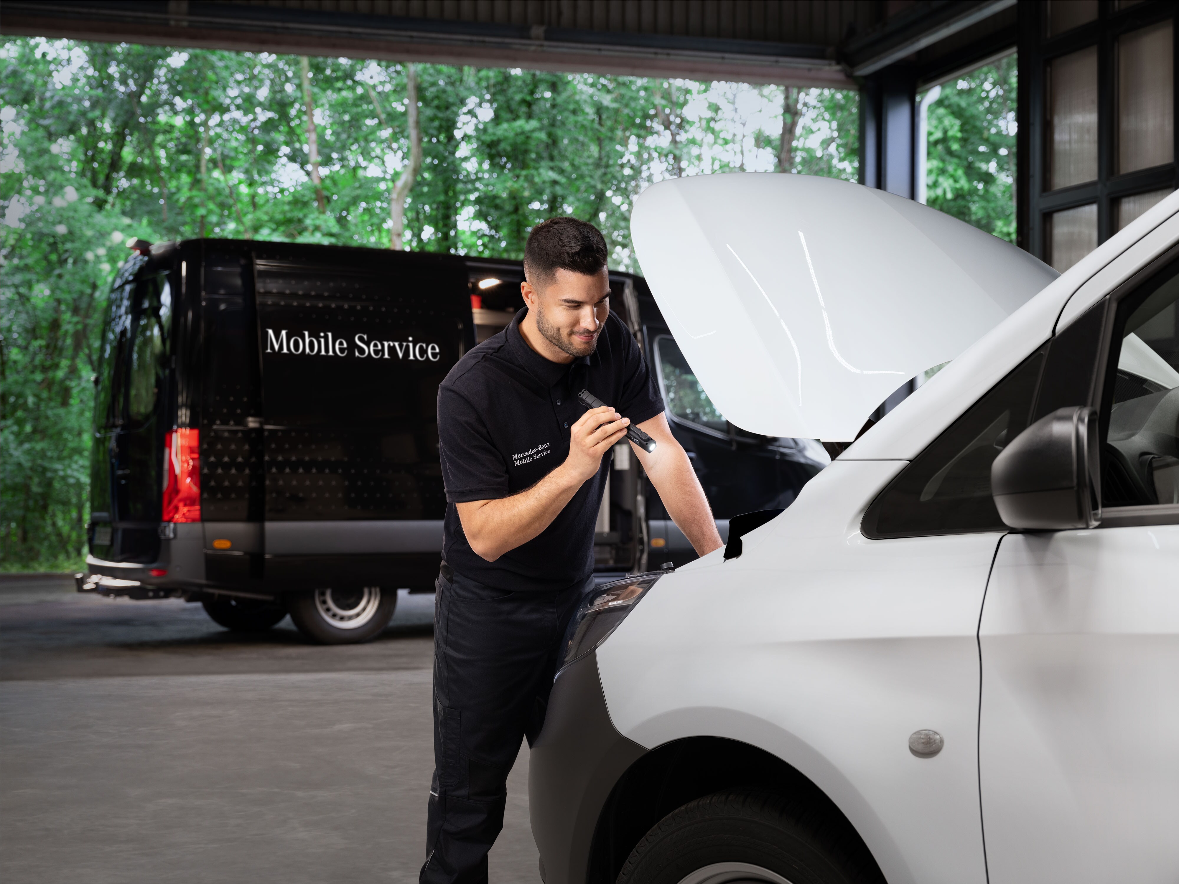 Mechanik vykonáva kontrolu motora na bielom úžitkovom vozidle Mercedes-Benz.