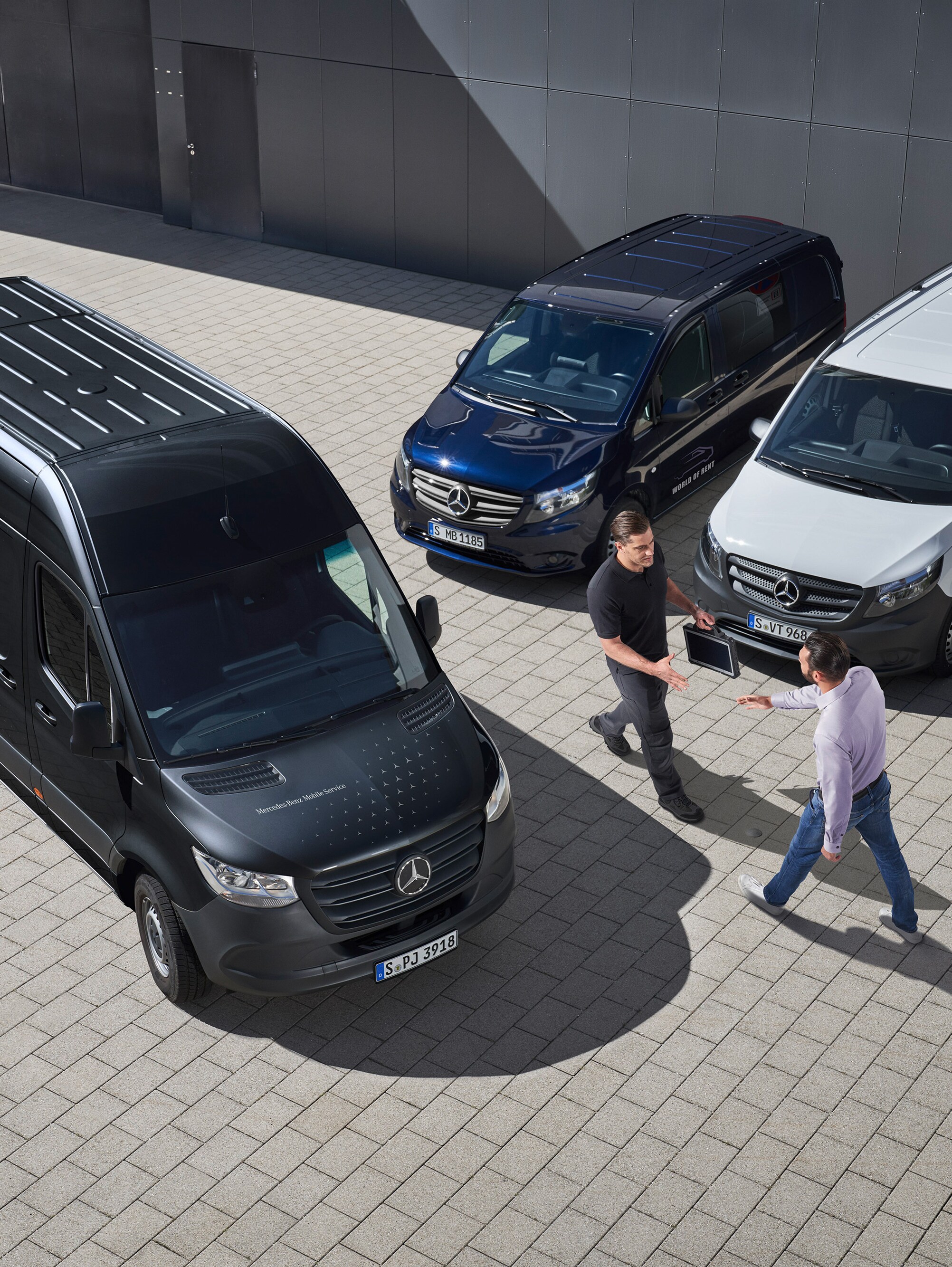 Dvaja muži sa zdravia medzi úžitkovými vozidlami Mercedes-Benz.