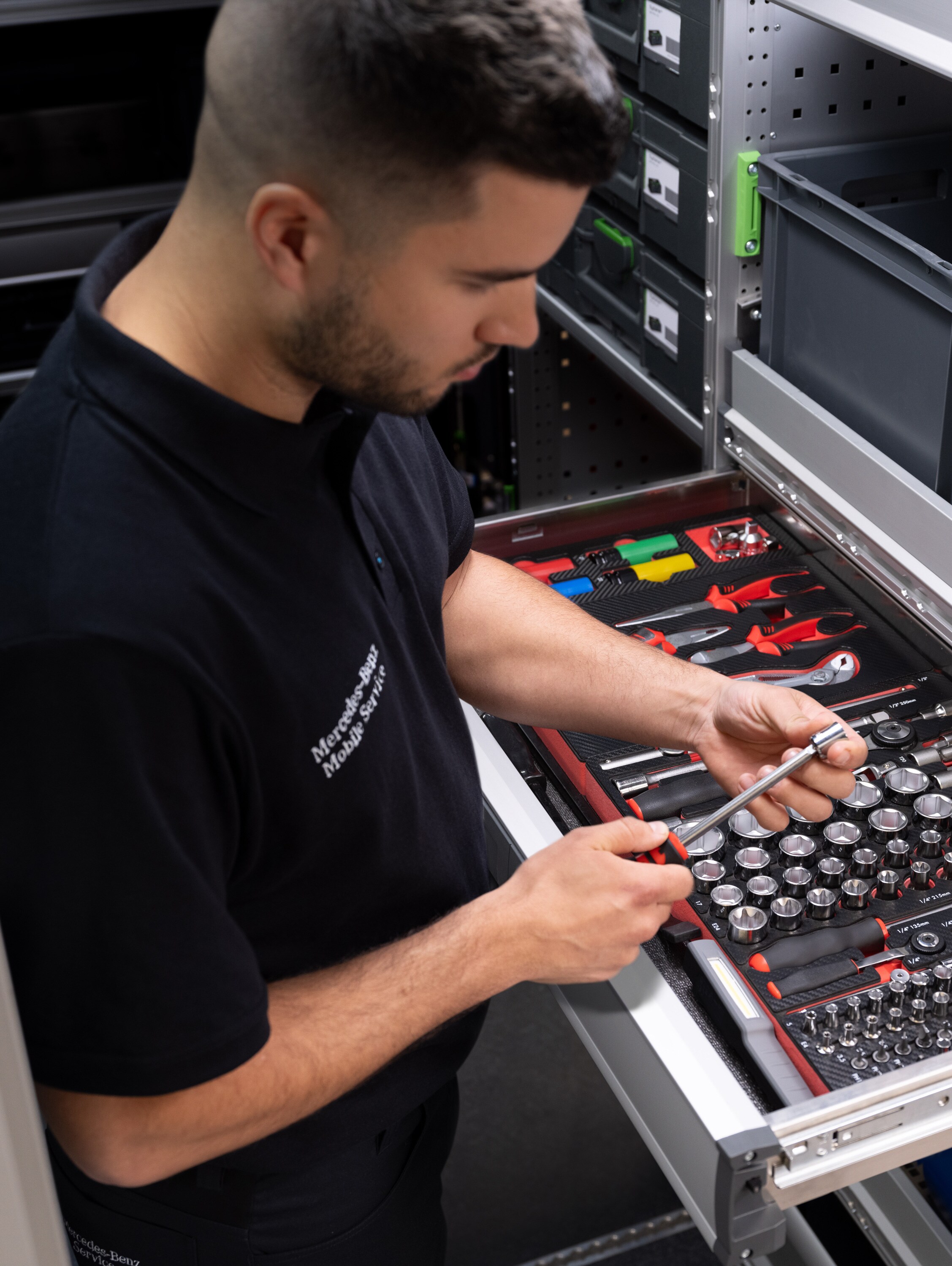 Technik vyberá predmet zo zásuvky plnej náradia.