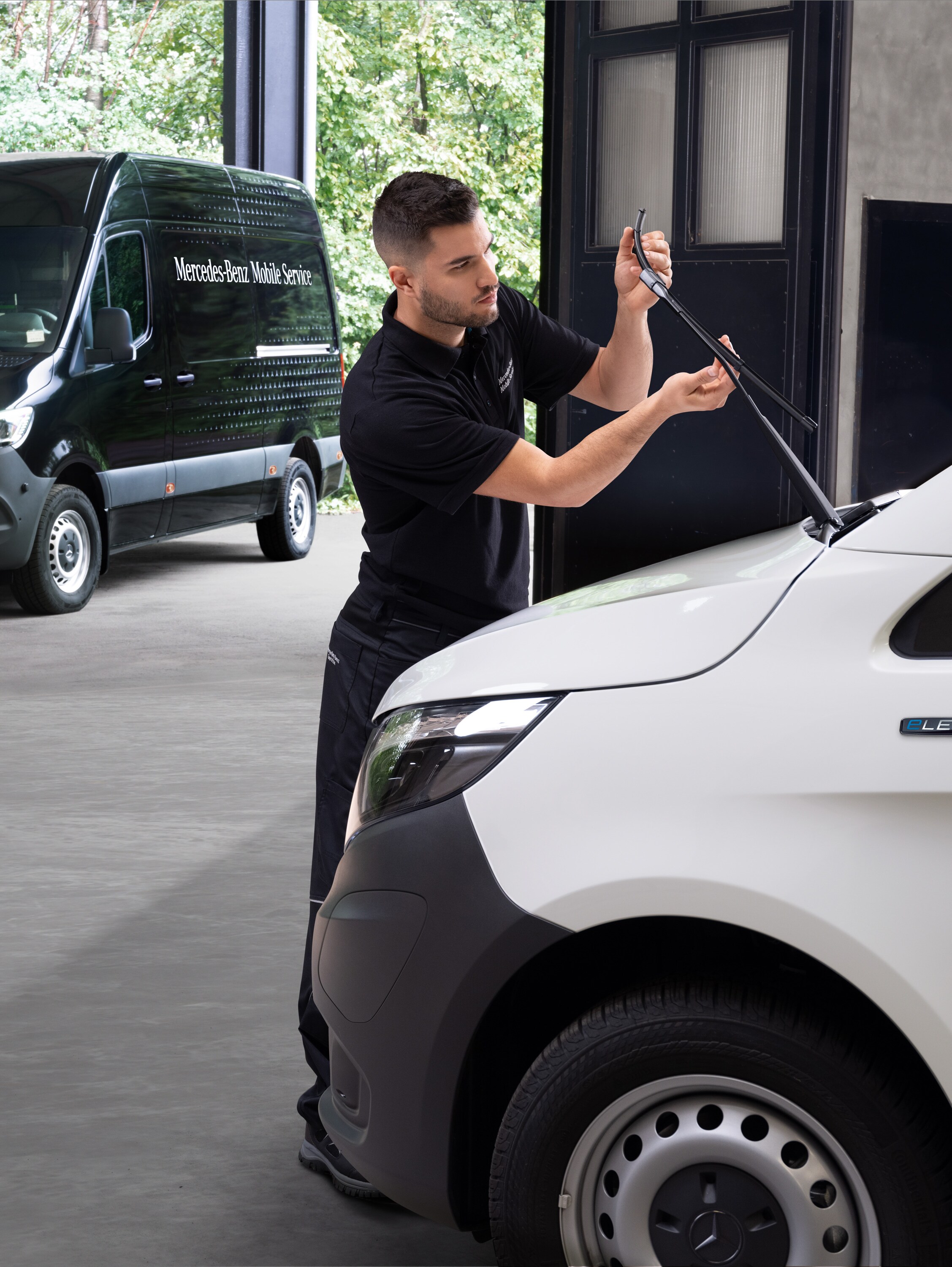 Technik vymieňa stieracie lišty na bielom úžitkovom vozidle Mercedes-Benz Vito.