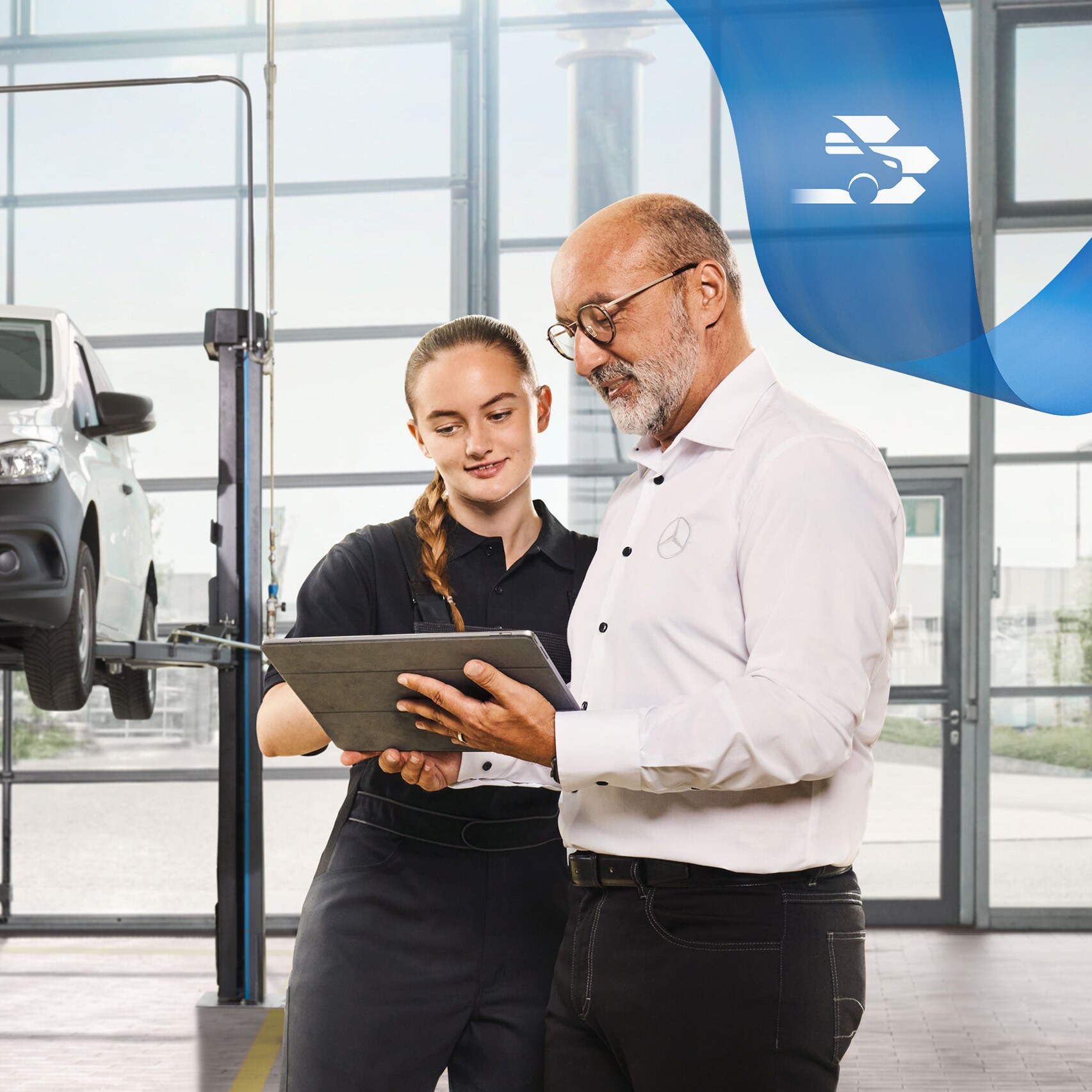 Dvaja zamestnanci diskutujú v dielni o servise úžitkového vozidla pri zdvihnutom úžitkovom vozidle Mercedes-Benz.