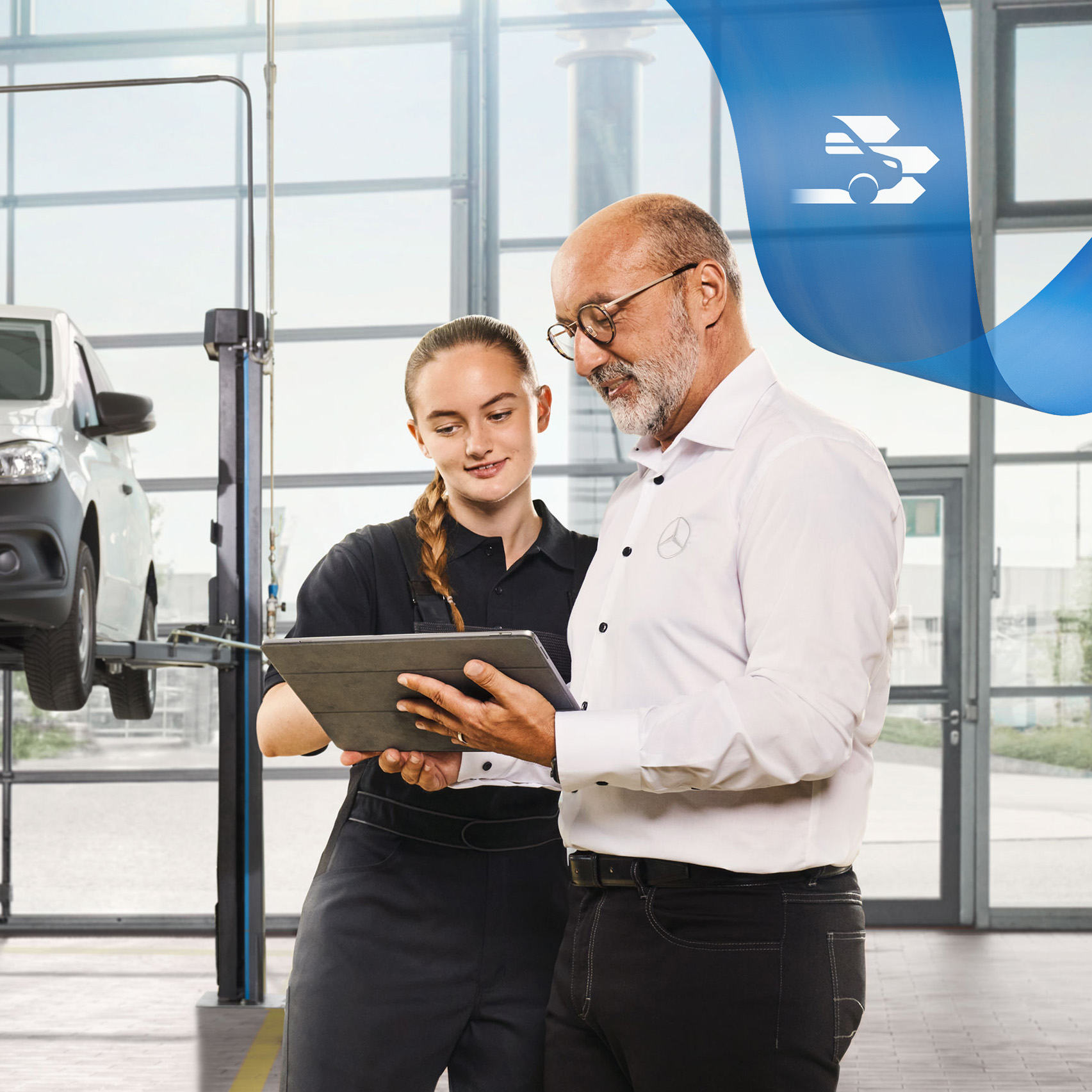 Mercedes-Benz | Údržba Dvaja zamestnanci diskutujú v dielni o servise úžitkového vozidla pri zdvihnutom úžitkovom vozidle Mercedes-Benz.