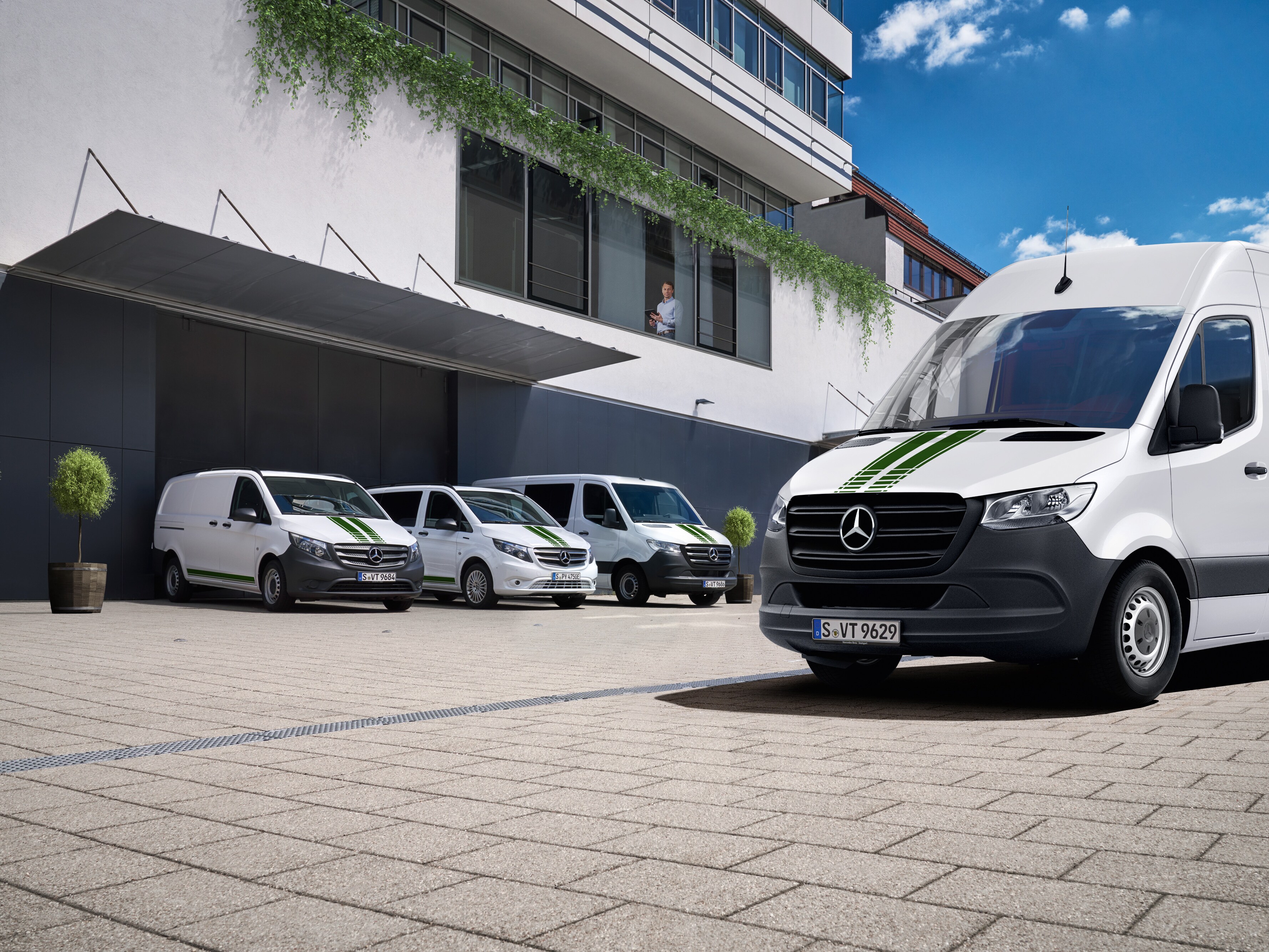 Autopark úžitkových vozidiel Mercedes-Benz pred budovou ako symbol digitálneho monitorovania vozového parku.