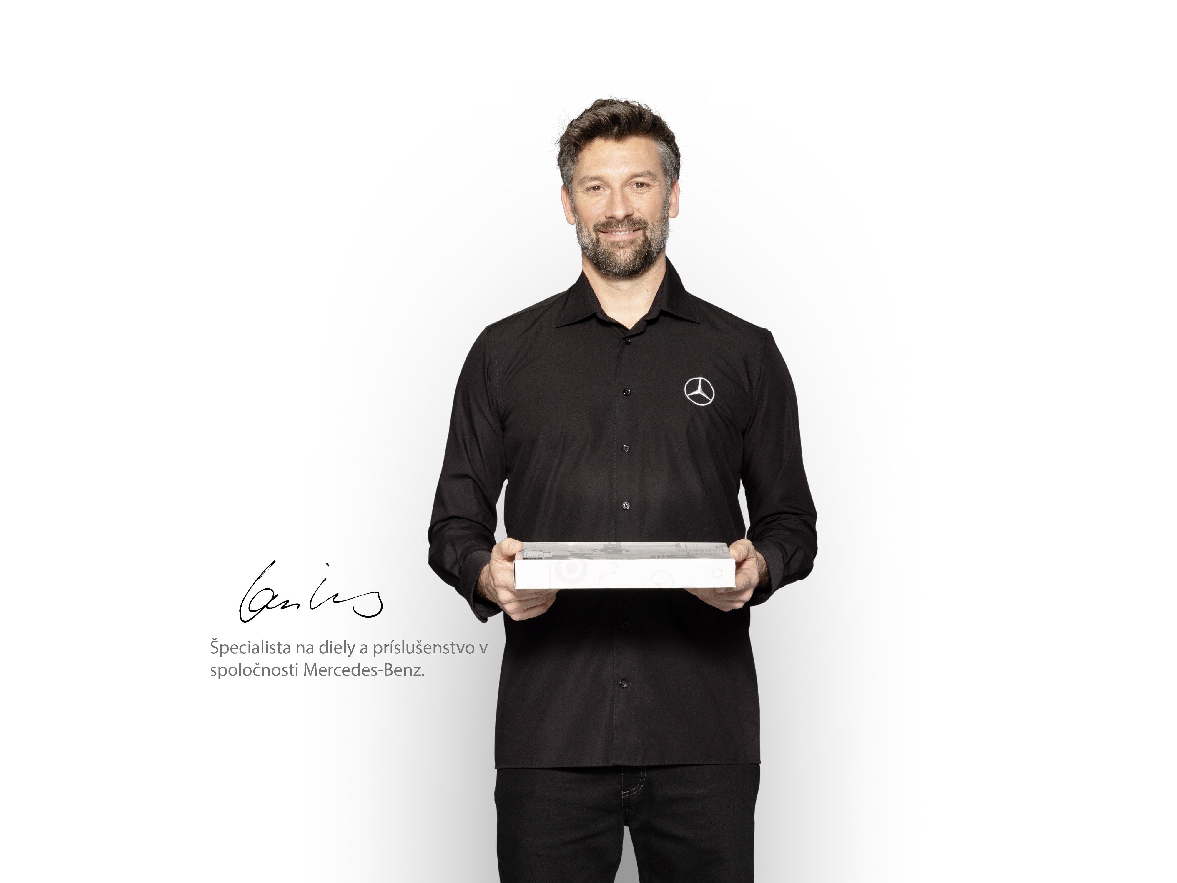 Interný technik Mercedes-Benz so škatuľou v&nbsp;ruke, aby ukázal originálne diely Mercedes-Benz.